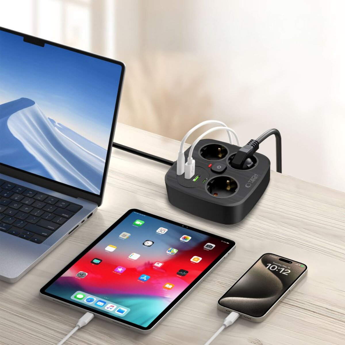 Ein Laptop, Tablet und Smartphone laden an einer schwarzen Steckdosenleiste.