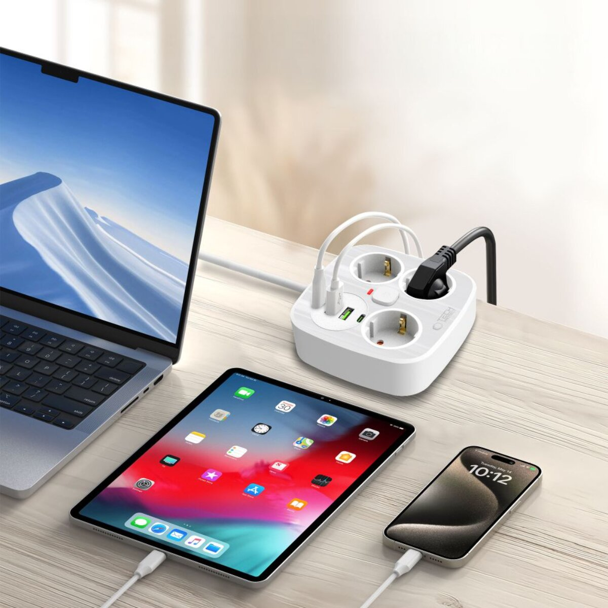 Ein Laptop, Tablet und Smartphone sind an eine weiße Steckdosenleiste angeschlossen.