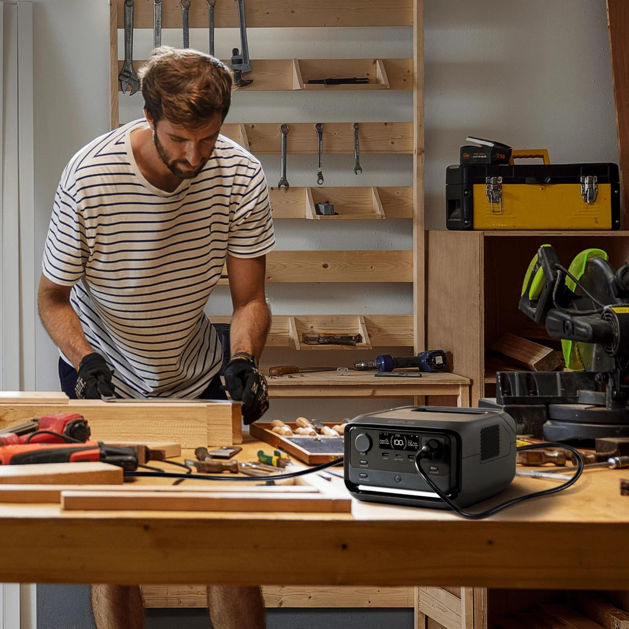 Ein Mann in einem gestreiften Hemd arbeitet an Holz in einer Werkstatt mit Werkzeugen.