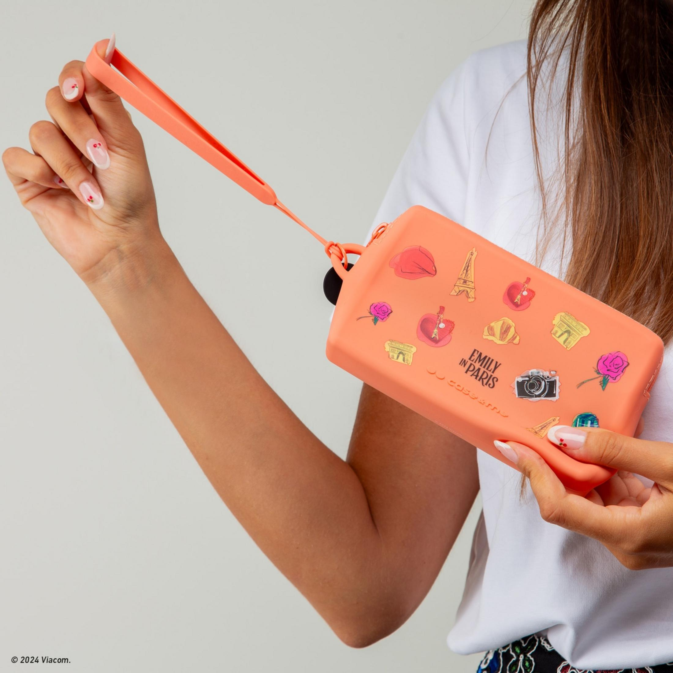 Una persona sostiene un bolso coral con motivos de la Torre Eiffel y rosas.