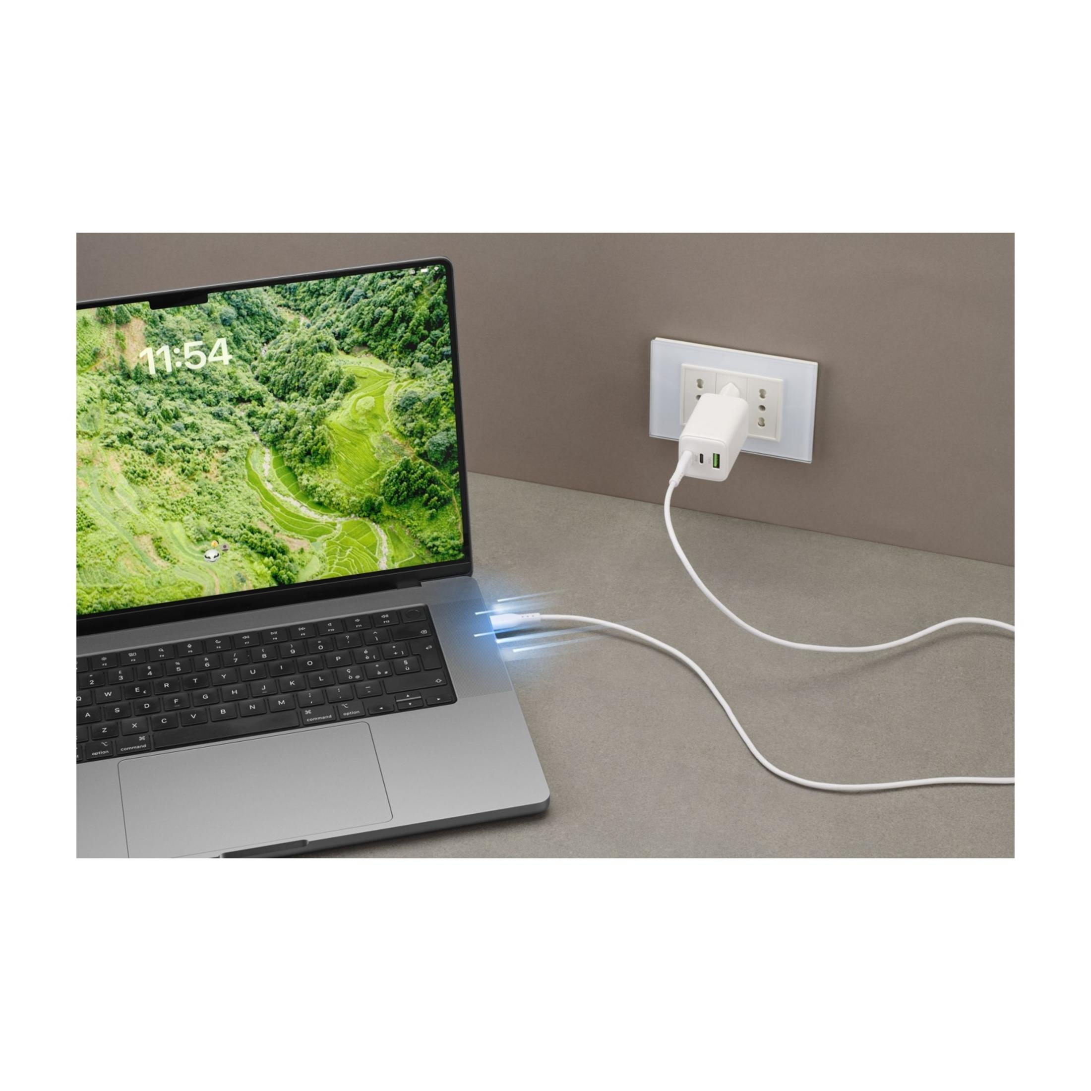 Ein Laptop wird über ein weißes USB-C-Ladegerät aufgeladen, das an eine Steckdose angeschlossen ist.