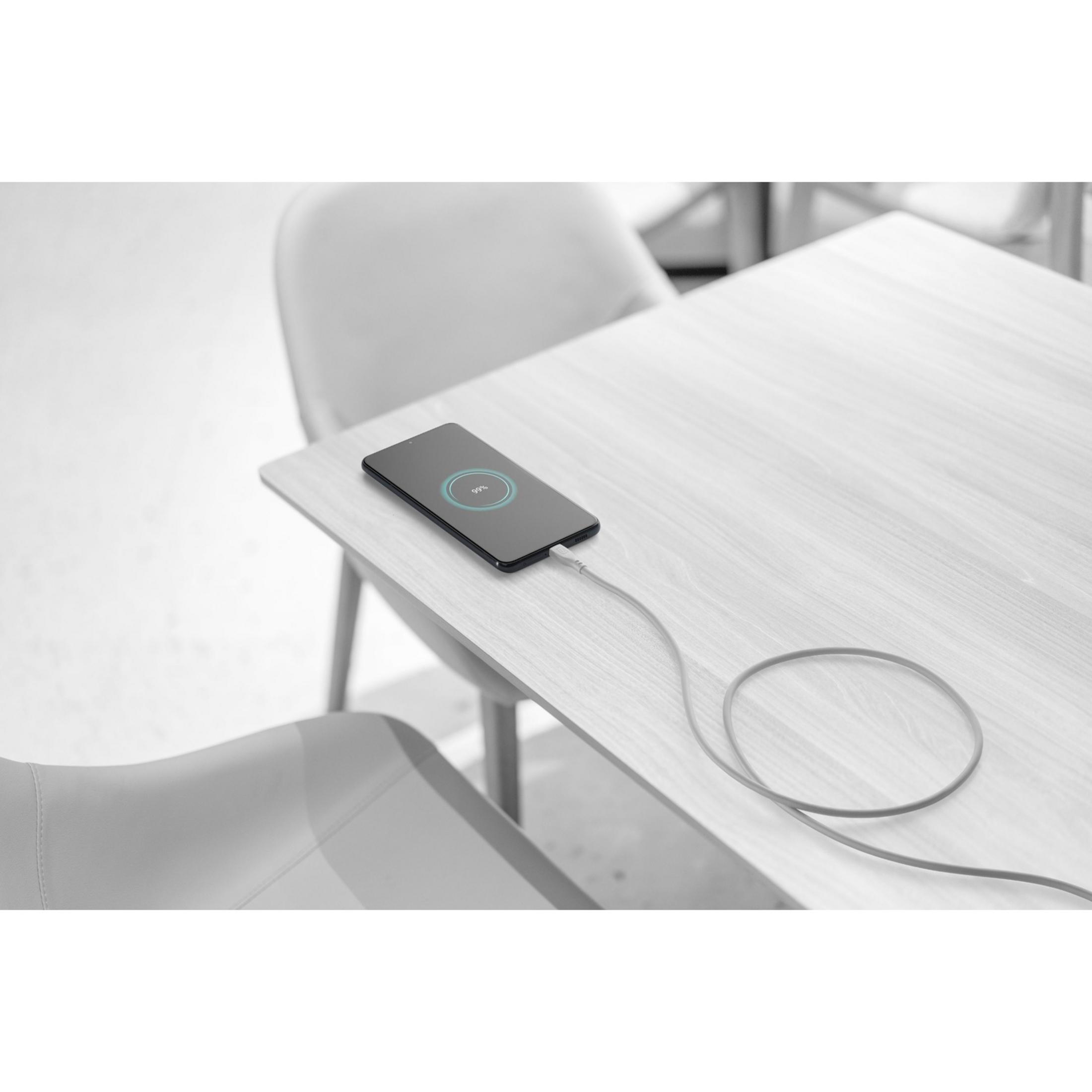 Een smartphone toont 99% lading op een houten tafel met aangesloten kabel.