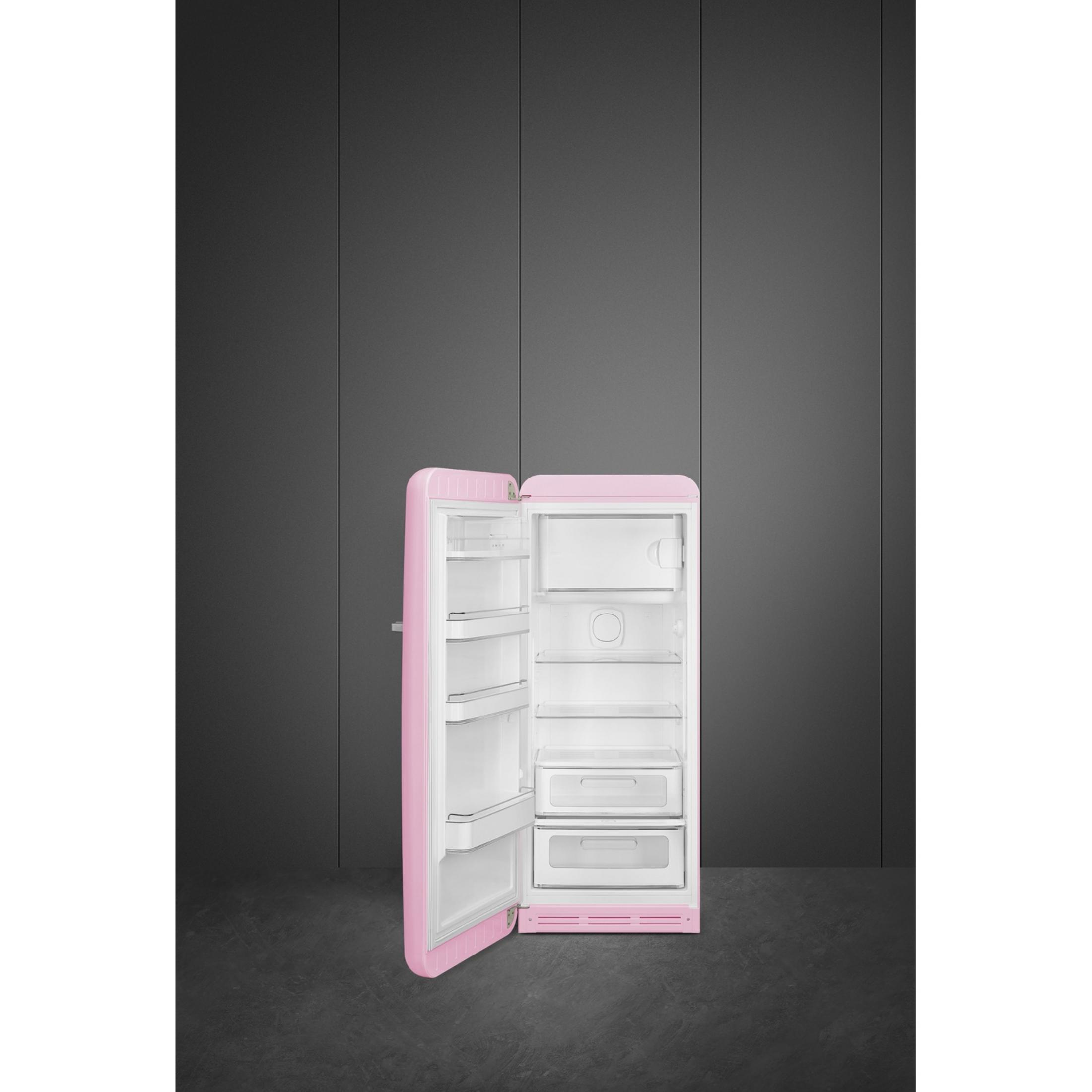 Un refrigerador abierto y rosa con estantes y cajones sobre un fondo oscuro.