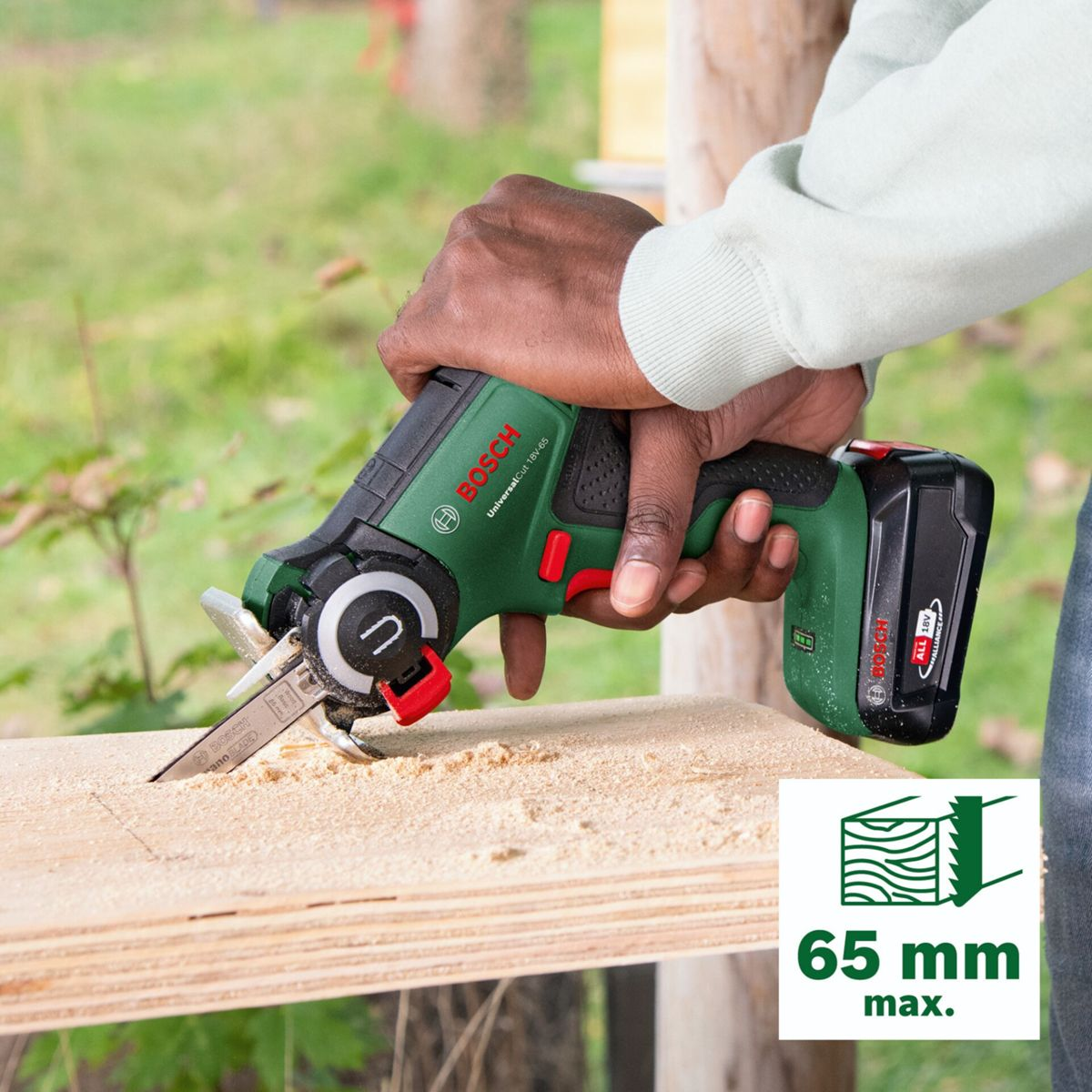 Ręka używa zielonej piły posuwowo-zwrotnej Bosch do cięcia drewna.