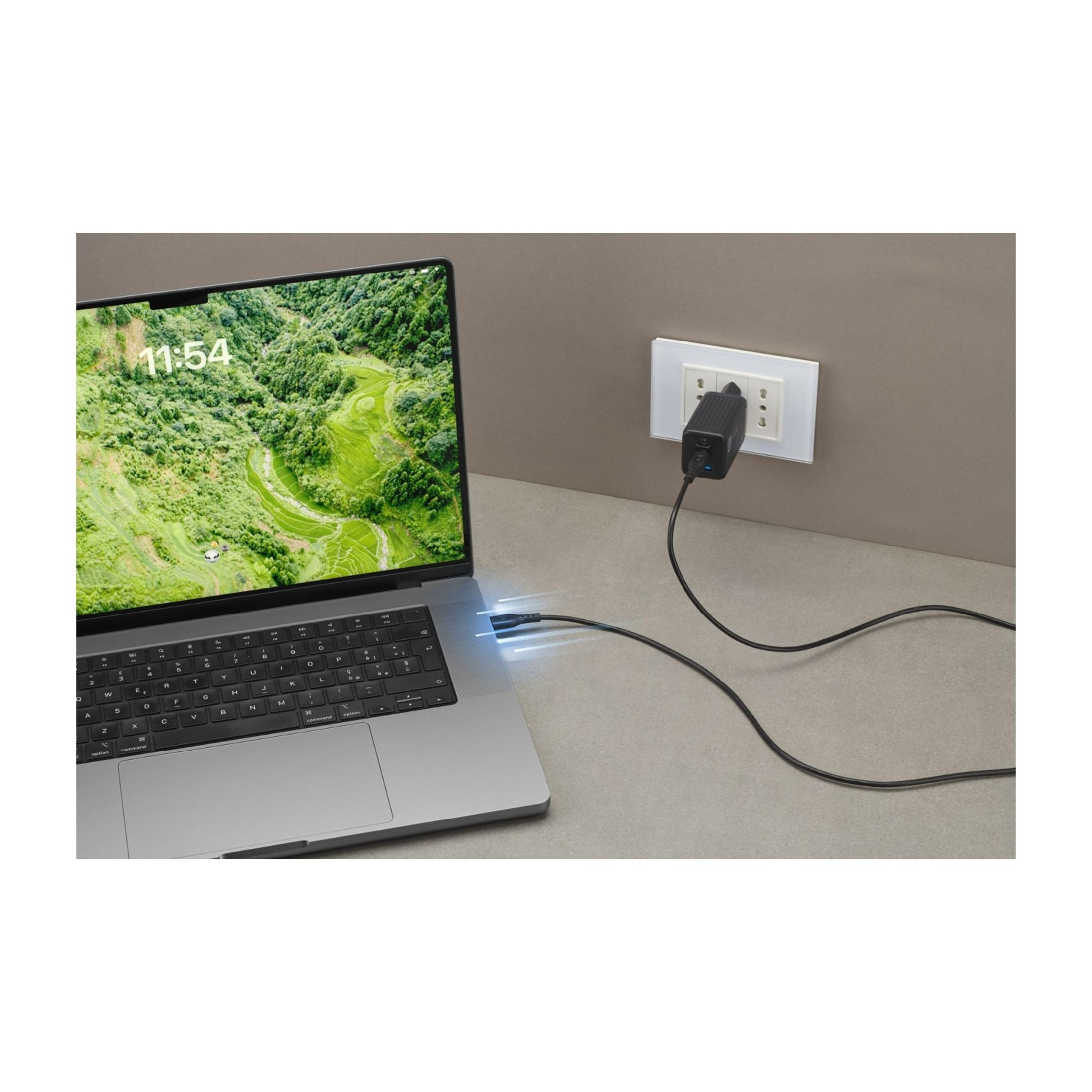 Ein Laptop ist an eine Steckdose angeschlossen. Ein Ladekabel verbindet sie.
