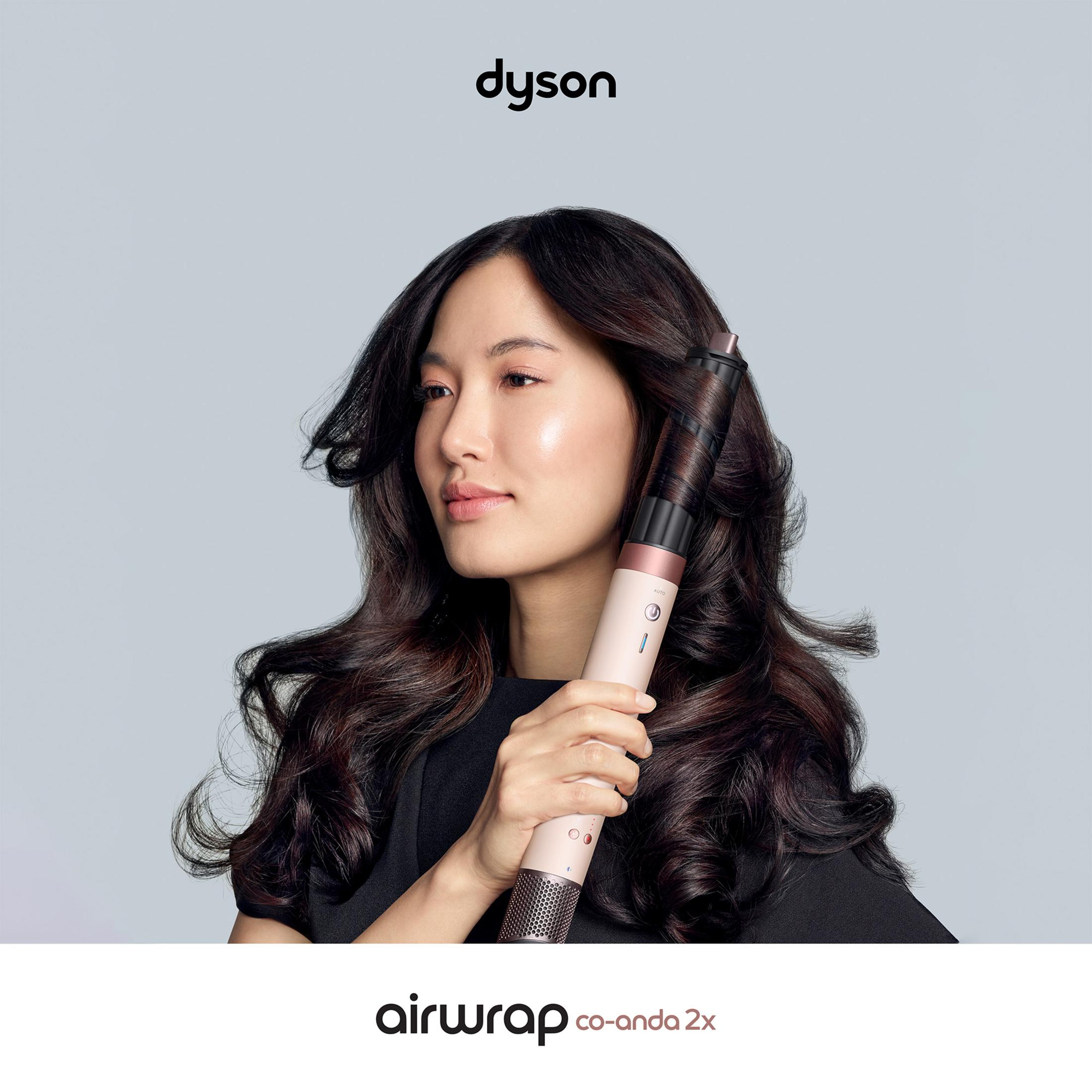 Kobieta z długimi, ciemnymi włosami stylizuje je za pomocą Dyson Airwrap.