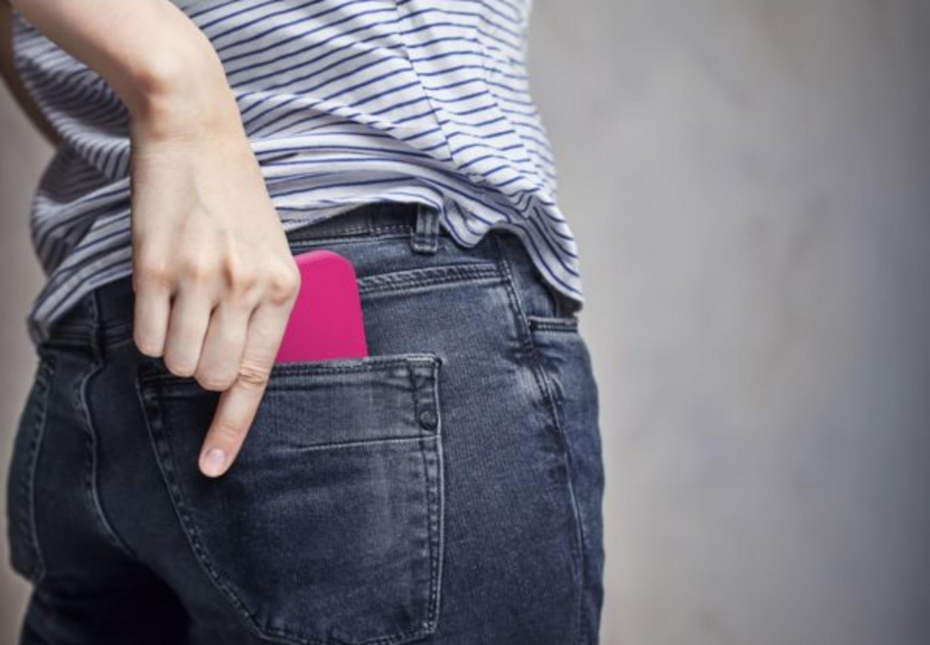 Una mano mette uno smartphone rosa nel taschino posteriore di un jeans blu.