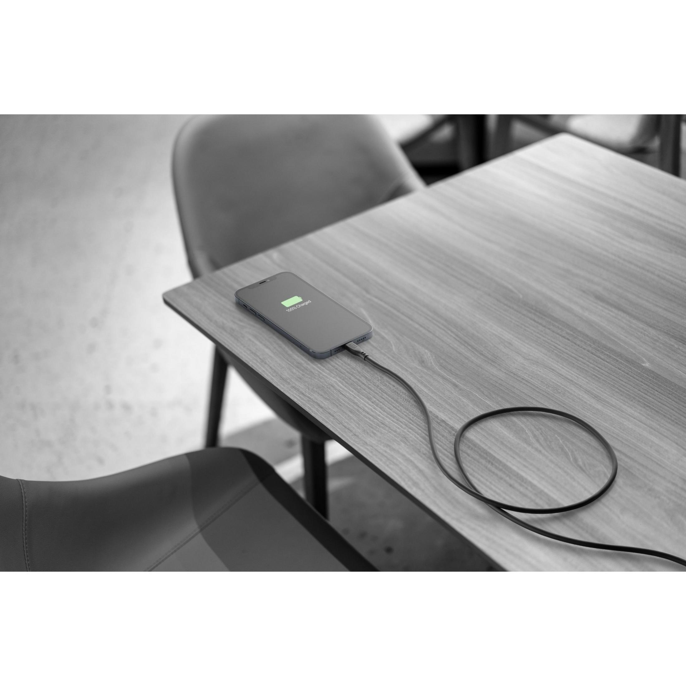 Un smartphone se charge sur une table en bois. La batterie est chargée à 100 %.