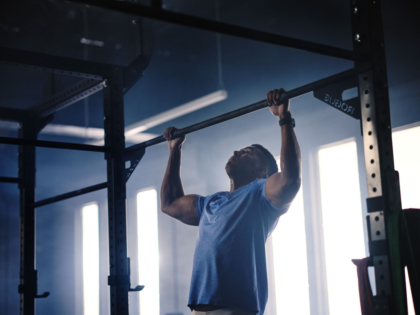 Mężczyzna wykonuje podciąganie na drążku na siłowni.