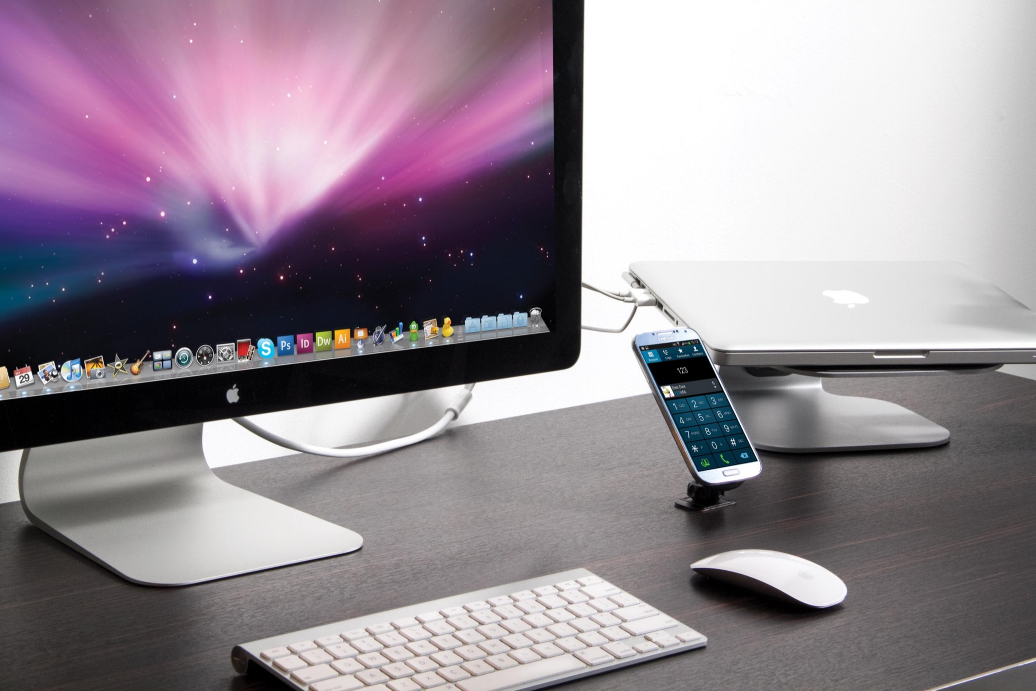Ein Schreibtisch mit einem iMac, MacBook, Tastatur, Maus und Telefon.