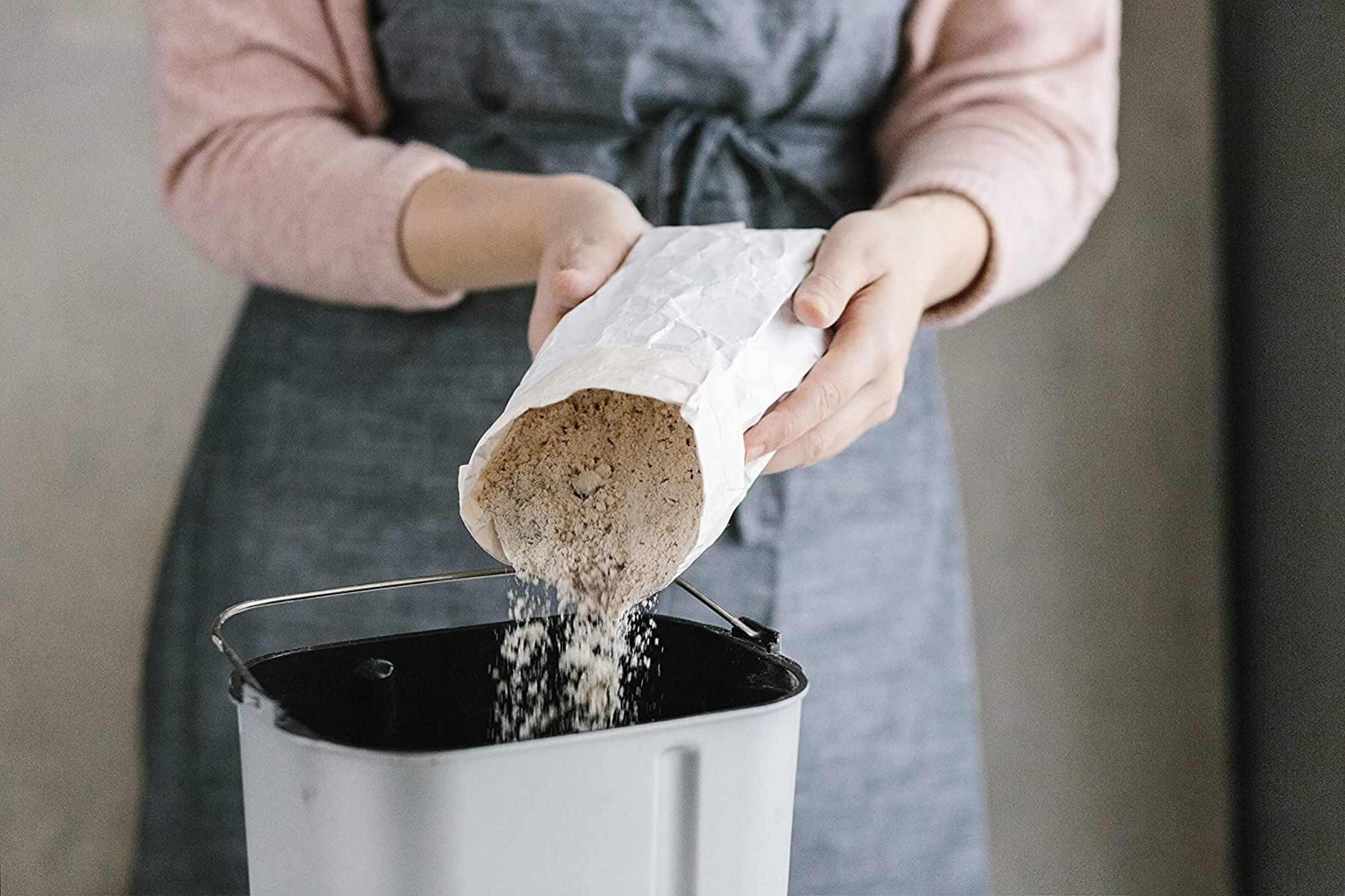 Eine Person schüttet Mehl aus einer Tüte in eine Brotbackmaschine.