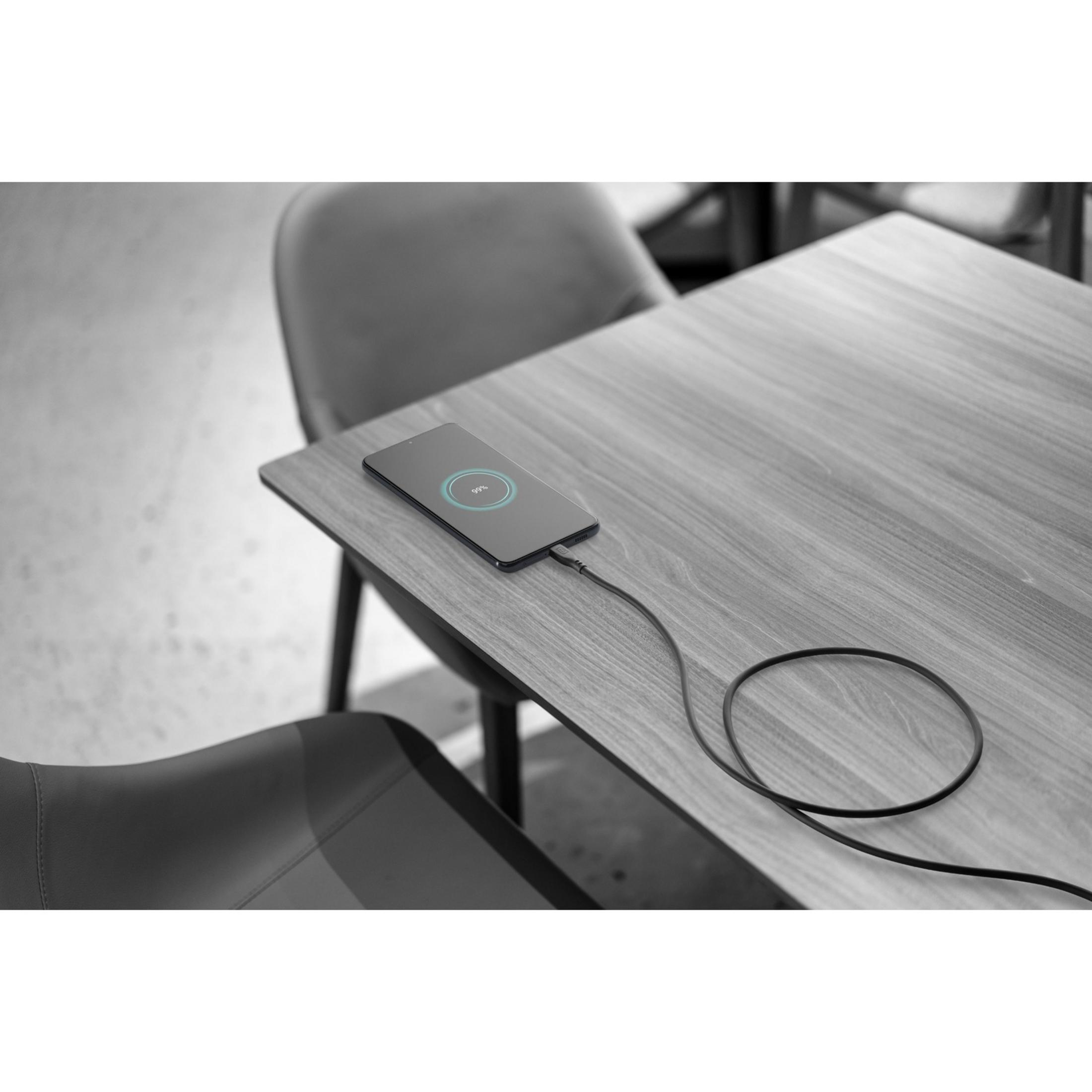 Een smartphone laadt op een houten tafel met een kabel.