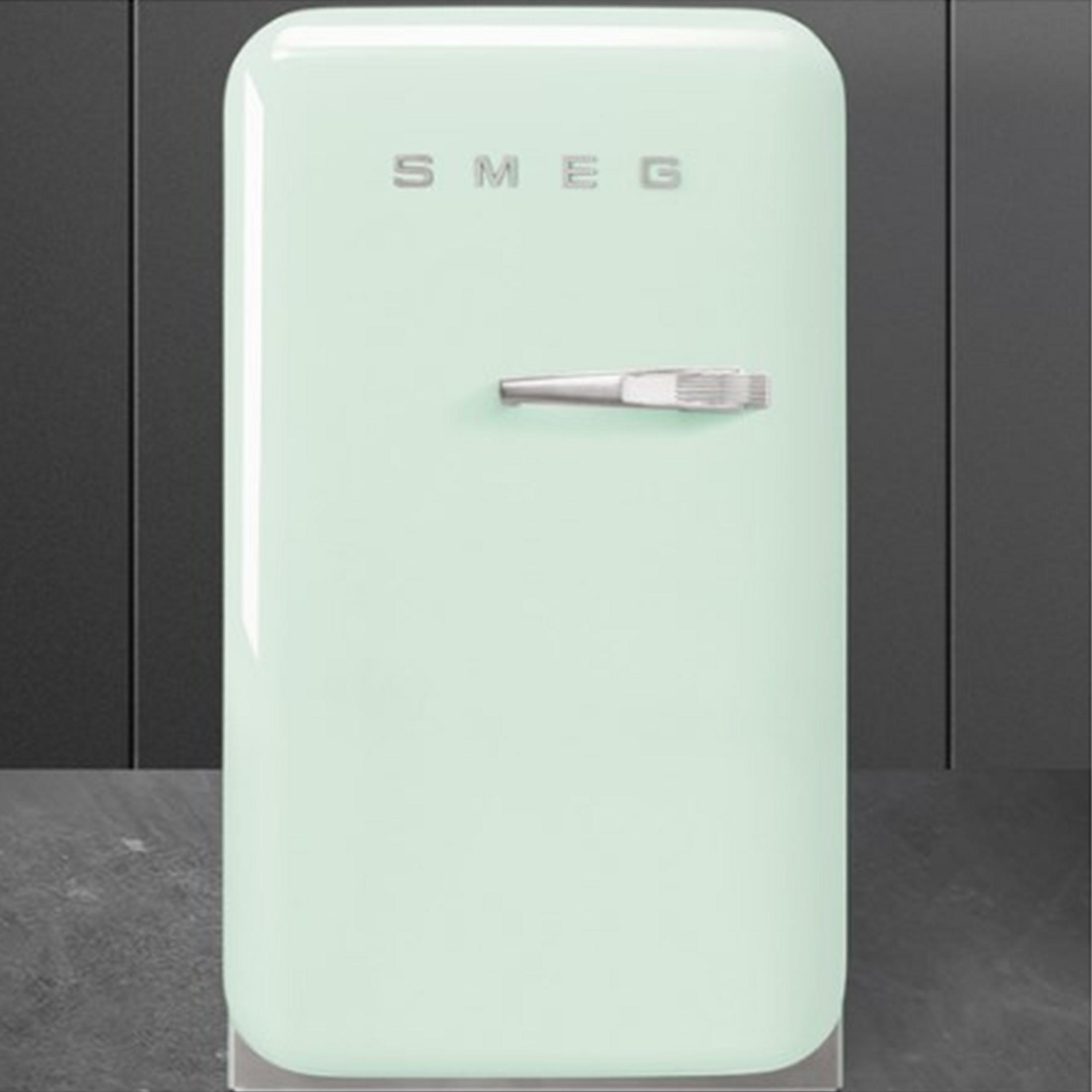 Un frigorifero Smeg verde chiaro con maniglia argentata su sfondo scuro.