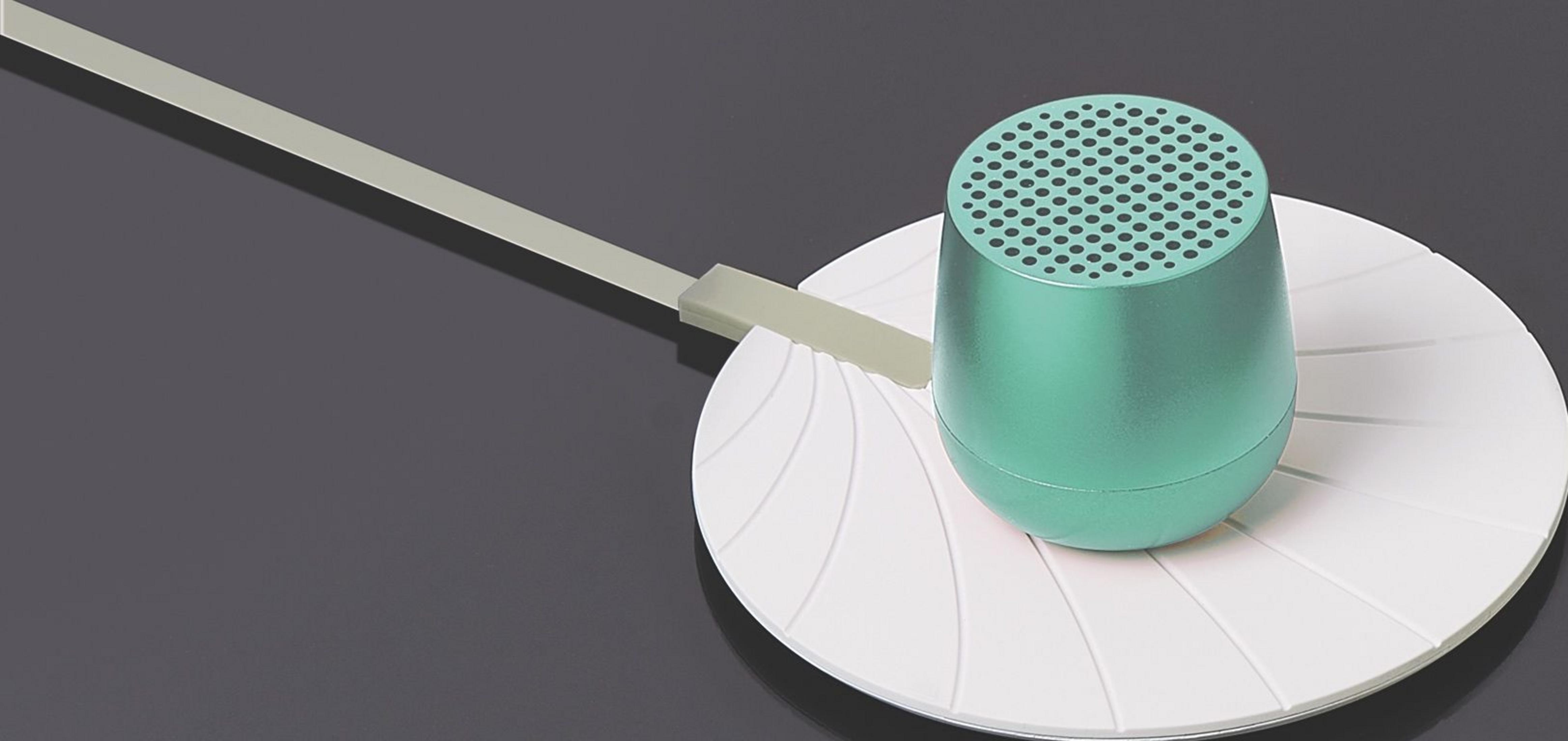 Un altoparlante verde è posato su una base bianca con linee.