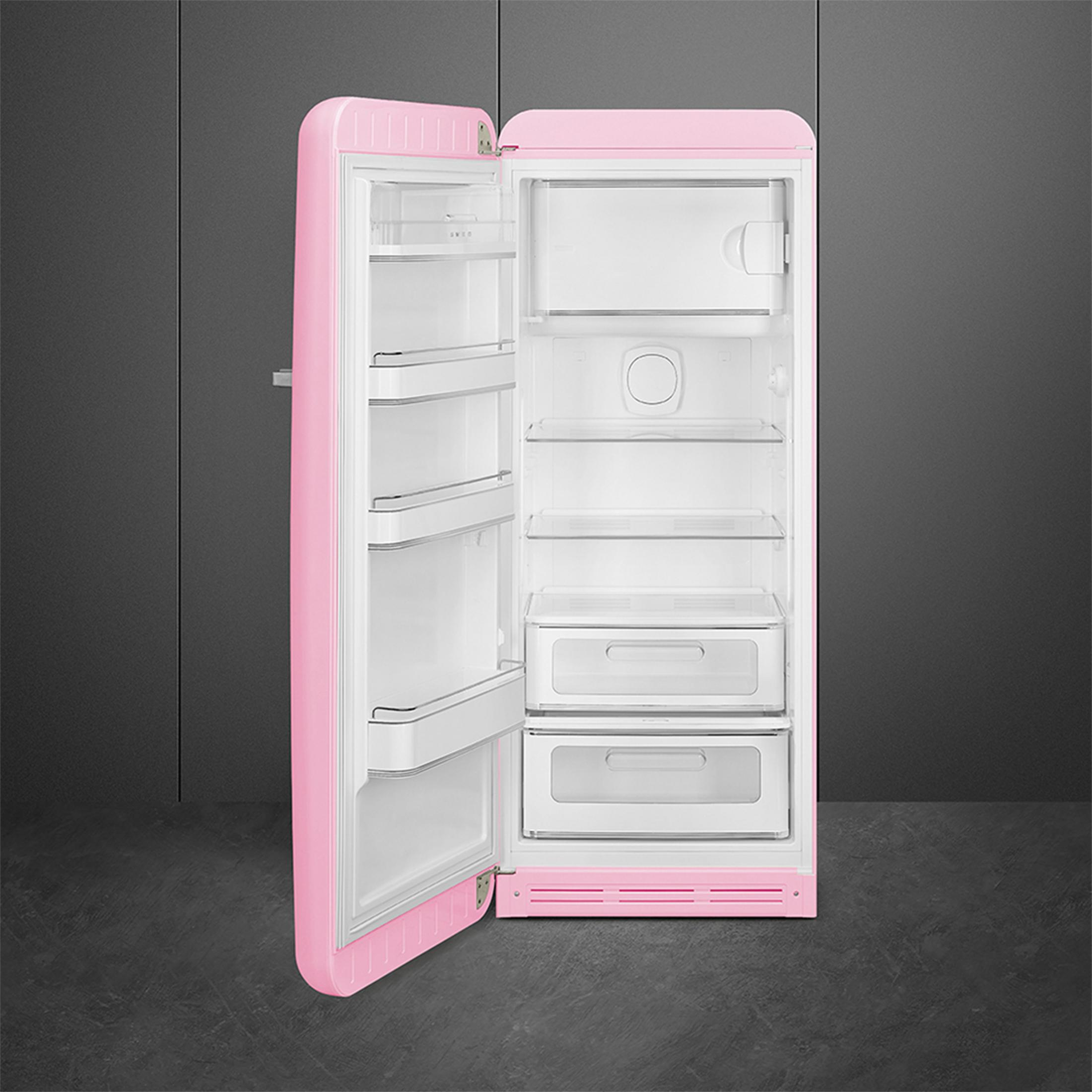 Un refrigerador rosa abierto con estantes y cajones blancos en el interior.