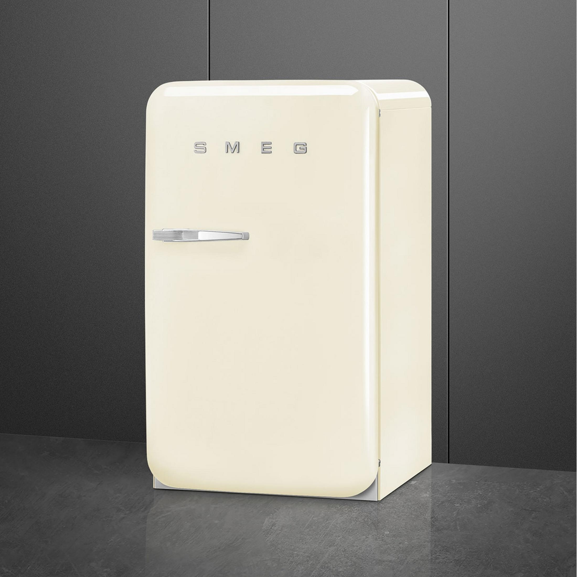 Un frigorífico Smeg color crema con asa plateada sobre suelo oscuro.