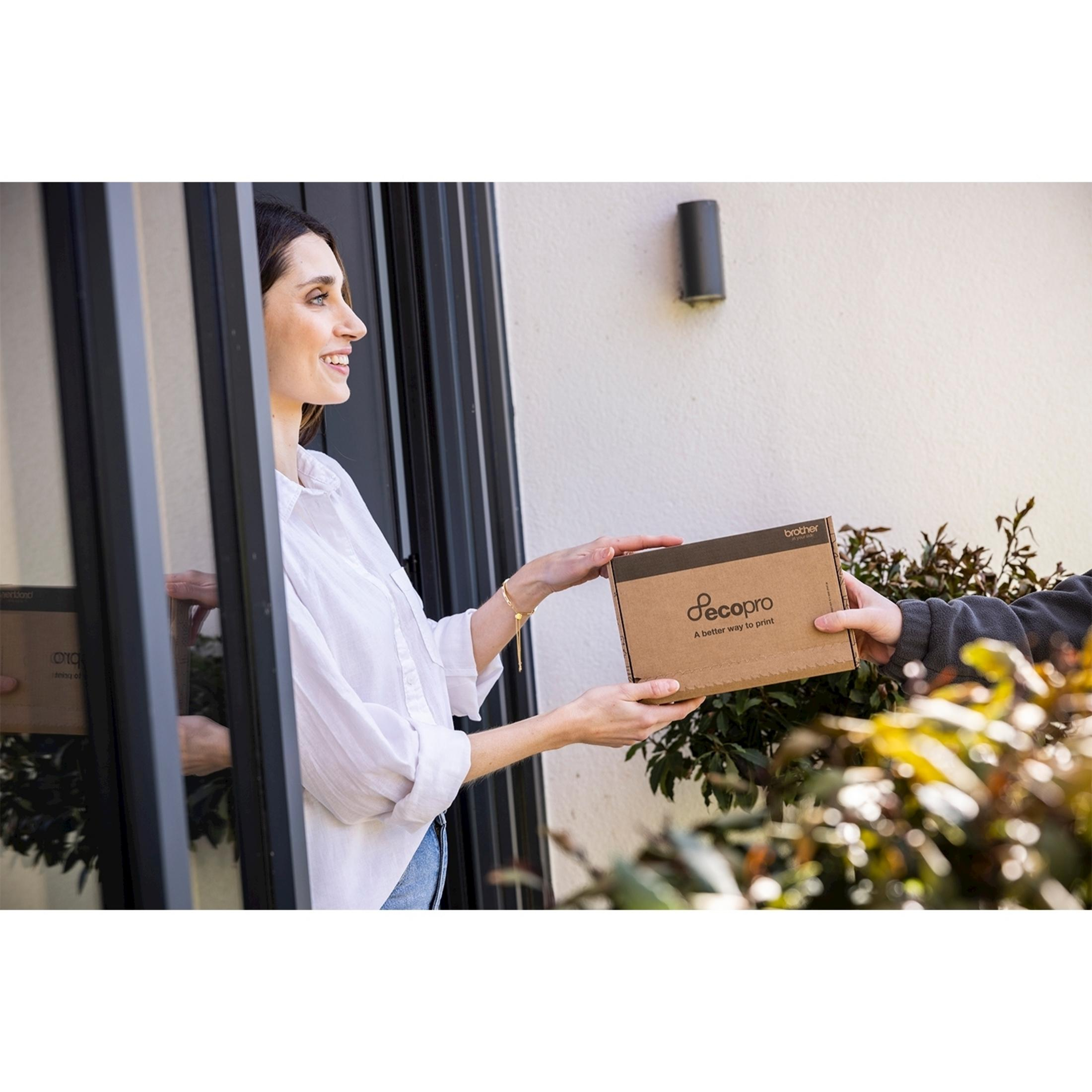 Kobieta otwiera drzwi, aby odebrać paczkę od listonosza.