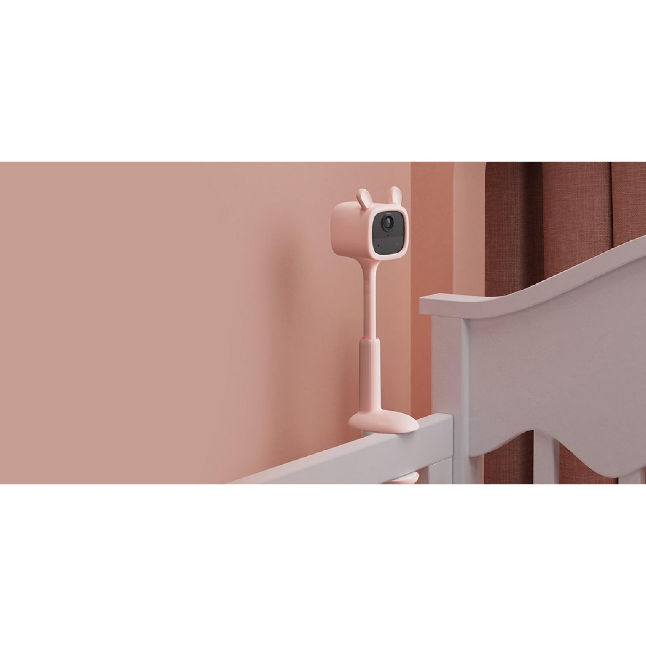 Ein rosafarbener Babyphone-Halter mit Hasenohren ist an einem weißen Gitterbett befestigt.