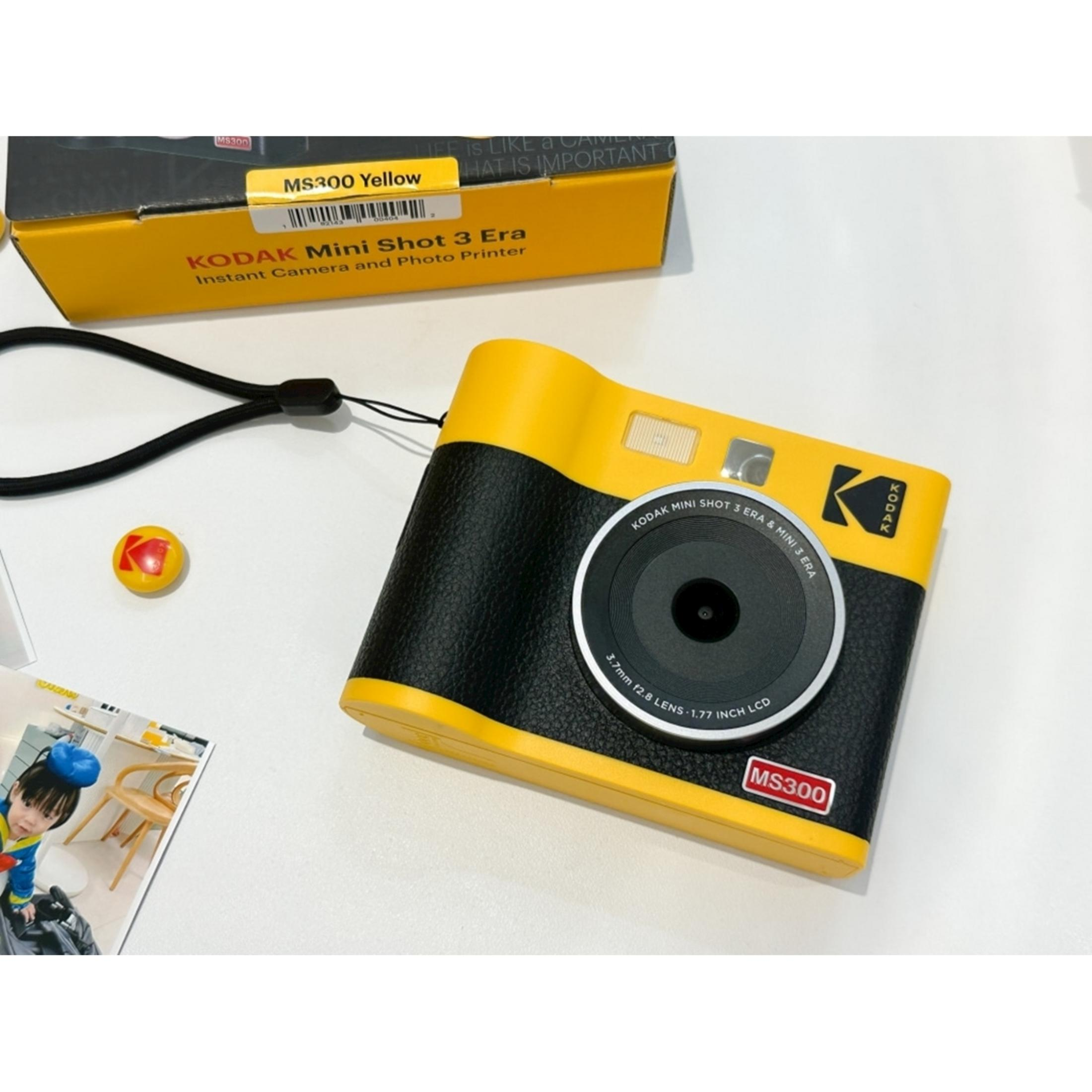Fotocamera Kodak Mini Shot 3 Era gialla con corpo effetto pelle nera e accessori.