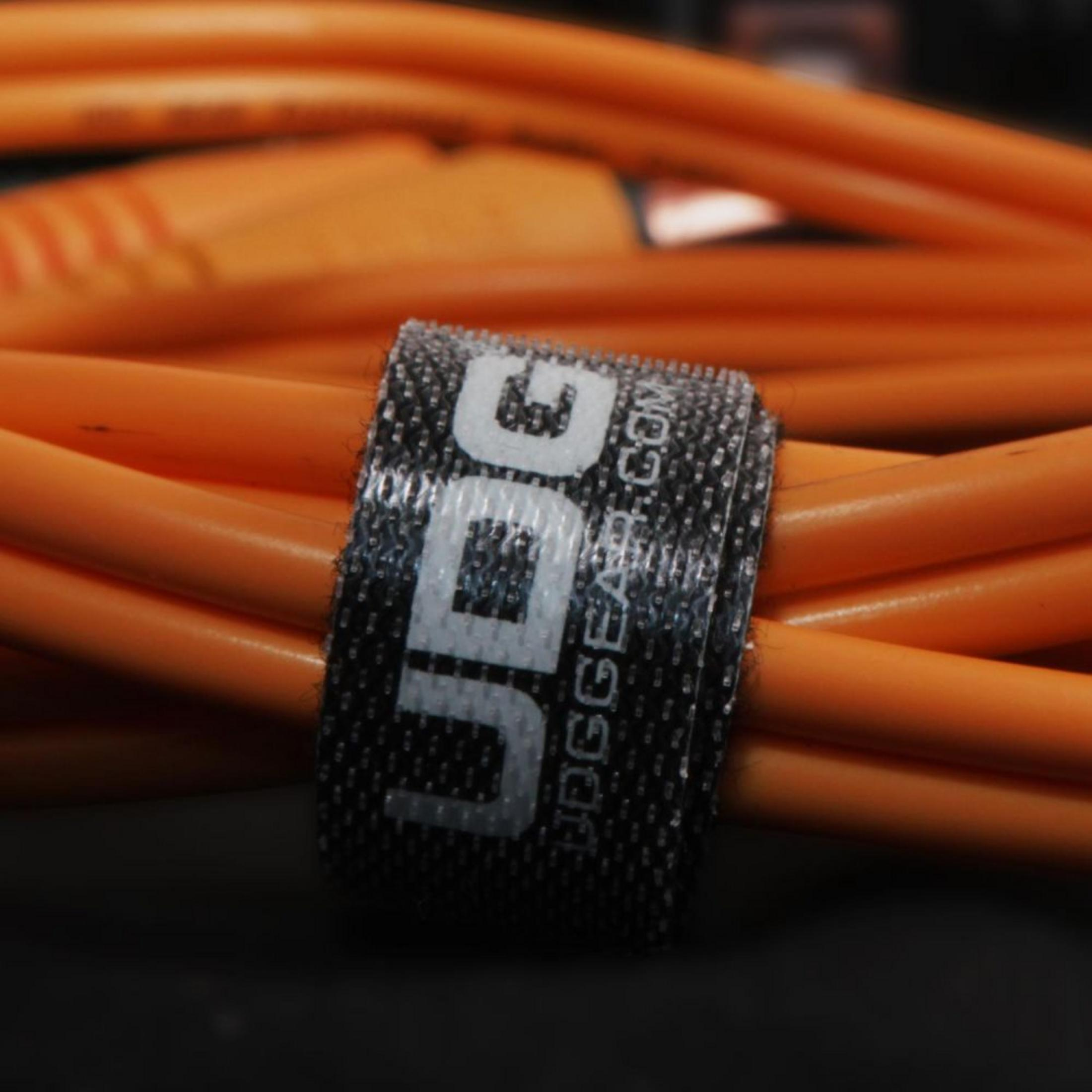 Ein Klettverschluss mit UDG-Logo bündelt orange Kabel.