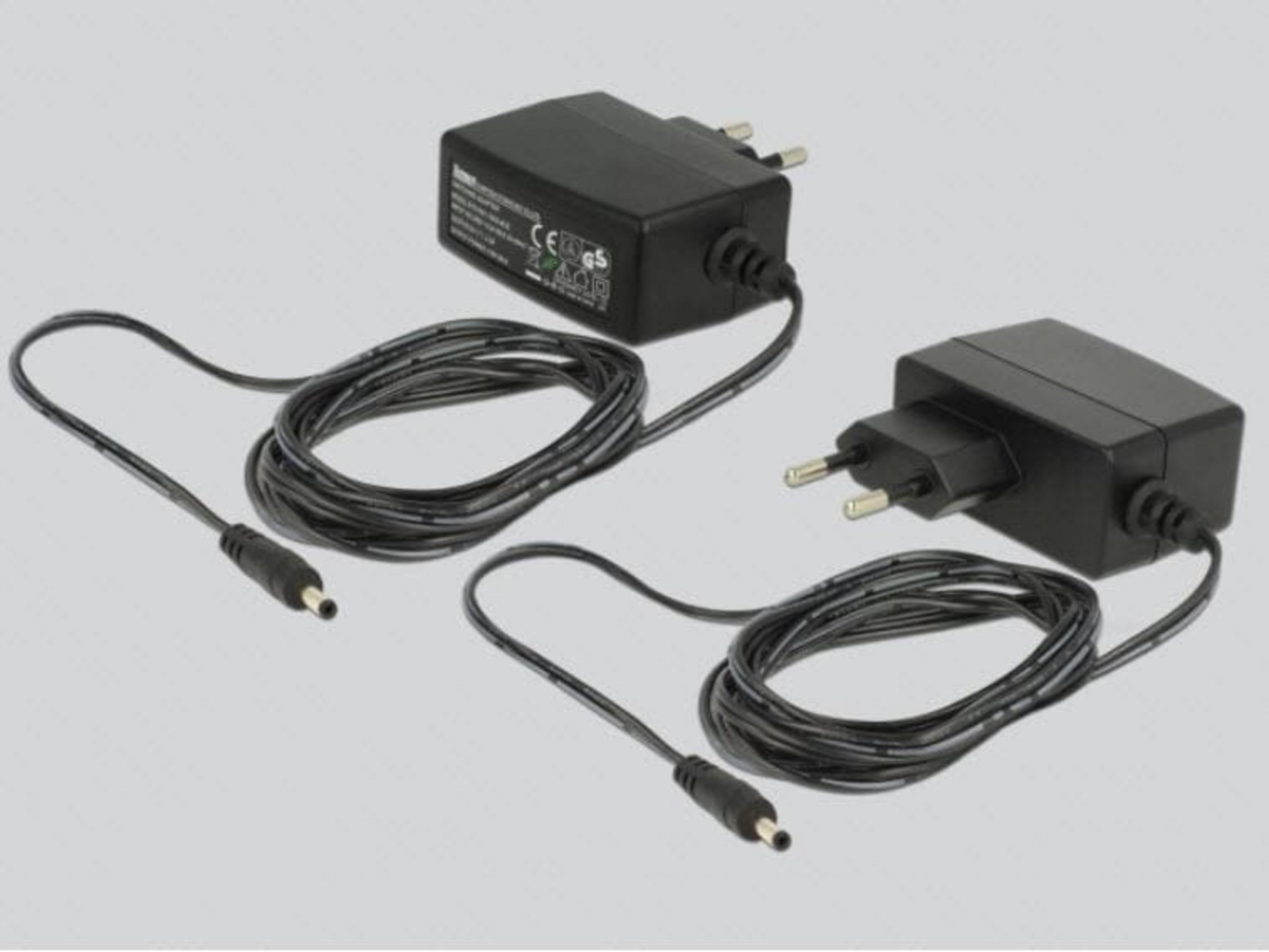 Zwei schwarze Netzadapter mit Kabeln und Steckern auf grauem Hintergrund.