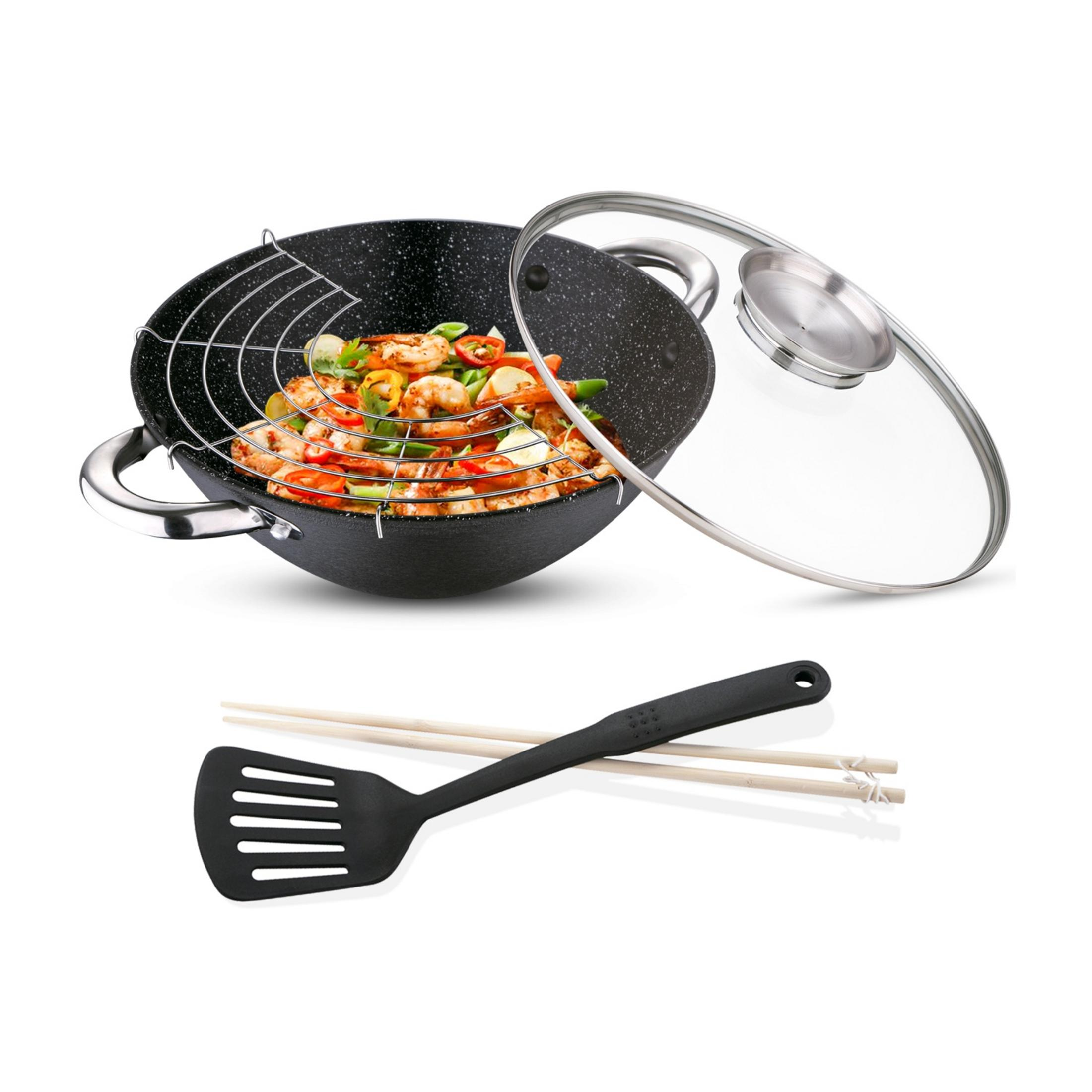 Un wok con gambas y verduras, una espátula y palillos al lado.
