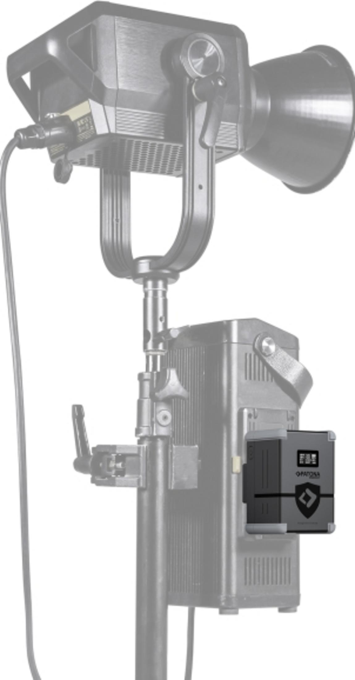 Un accessorio per fotocamera nero con logo a scudo è attaccato a un supporto per luci.