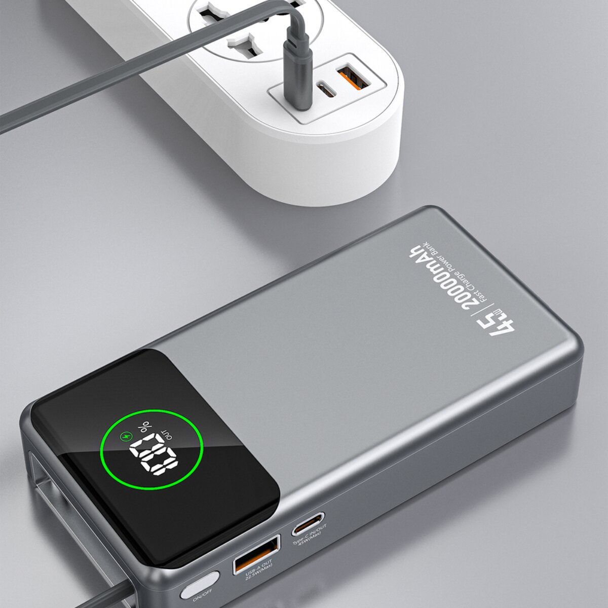 Grauer Powerbank mit 20000mAh, aufgeladen an weißer Steckdosenleiste.