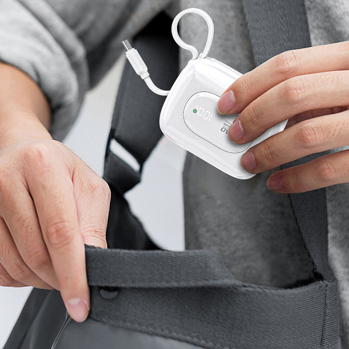 Weiße Powerbank mit Ladekabel wird in eine Tasche gesteckt.