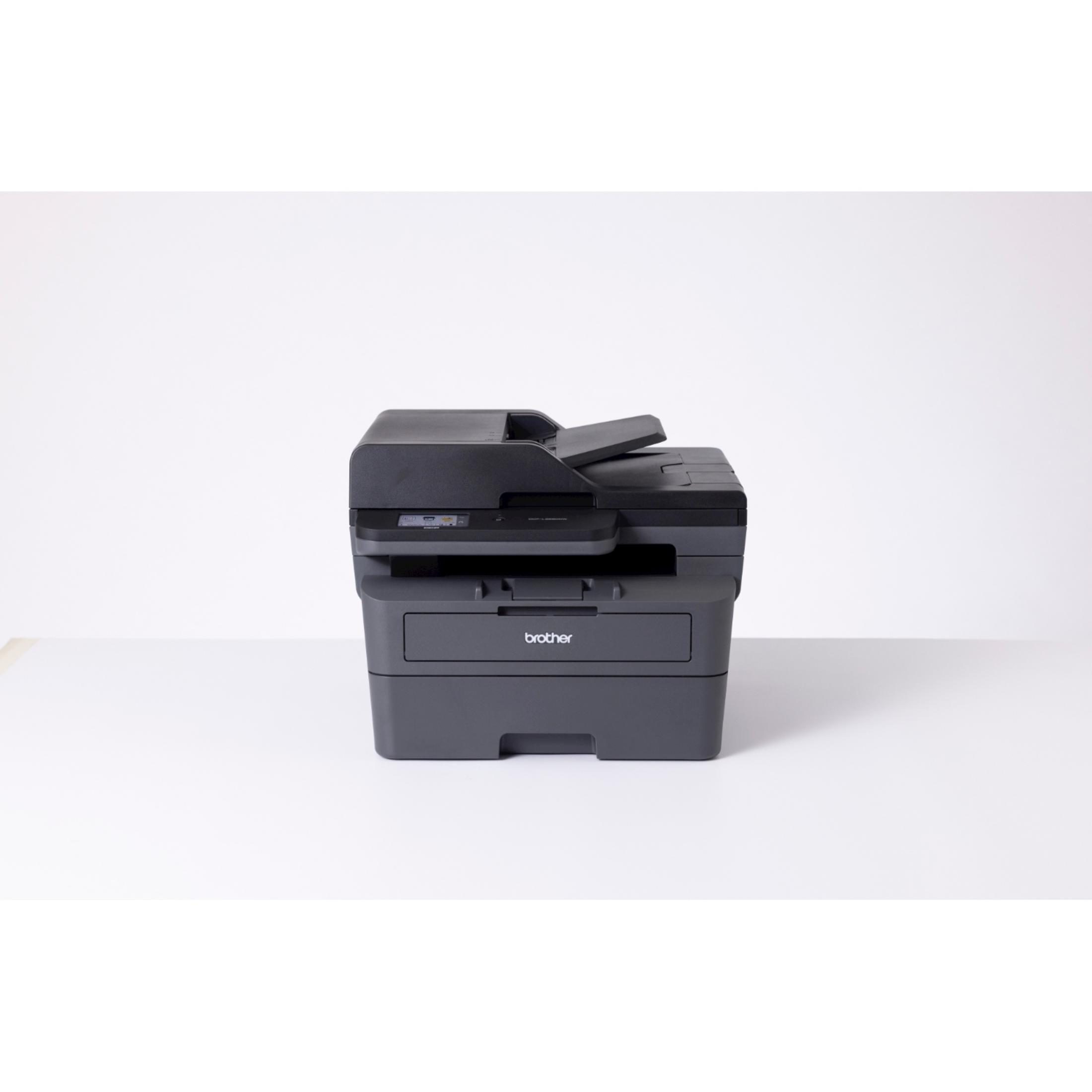 Czarna drukarka Brother ze skanerem i kopiarką stoi na białym stole.