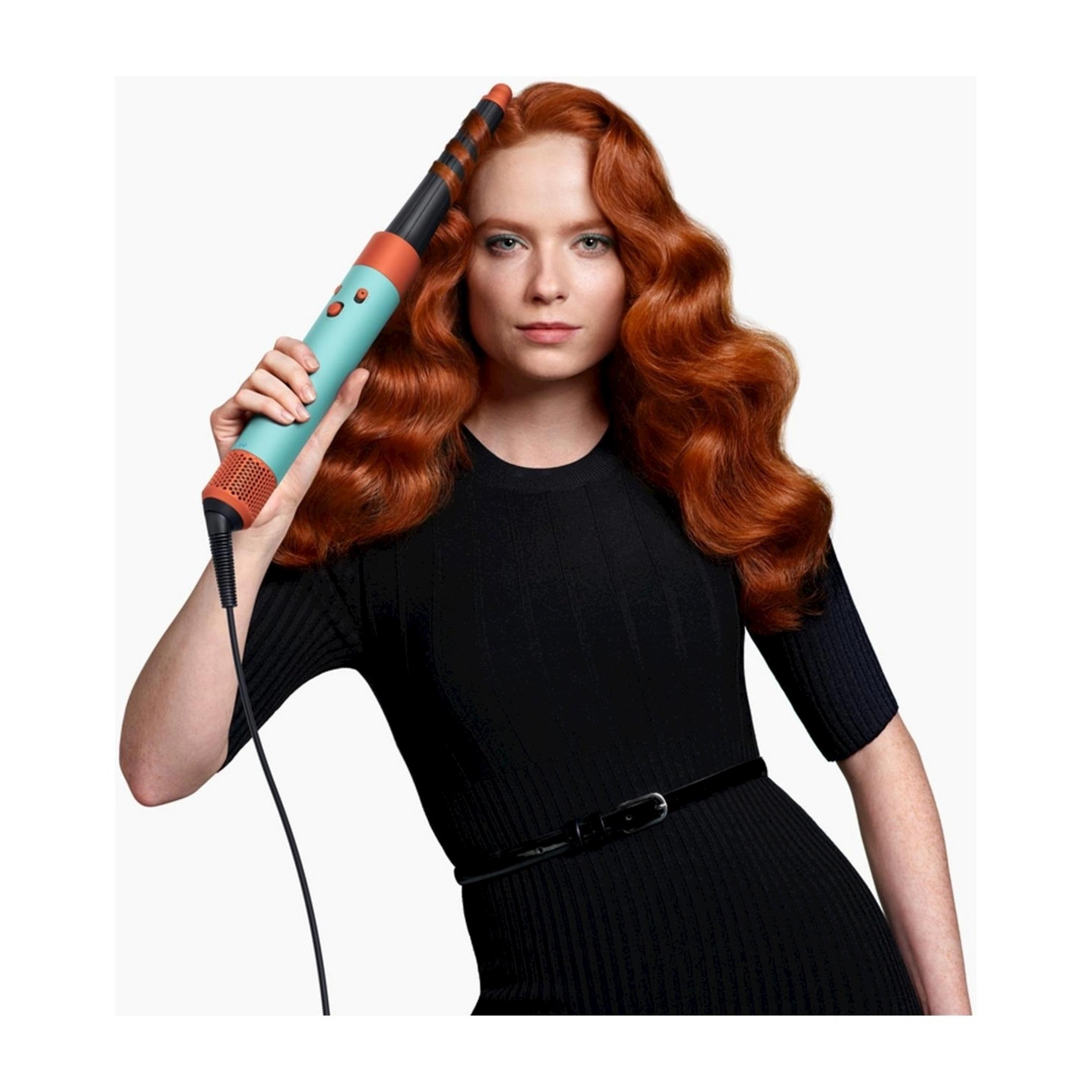 Kobieta z rudymi włosami trzyma turkusowe urządzenie do stylizacji włosów.