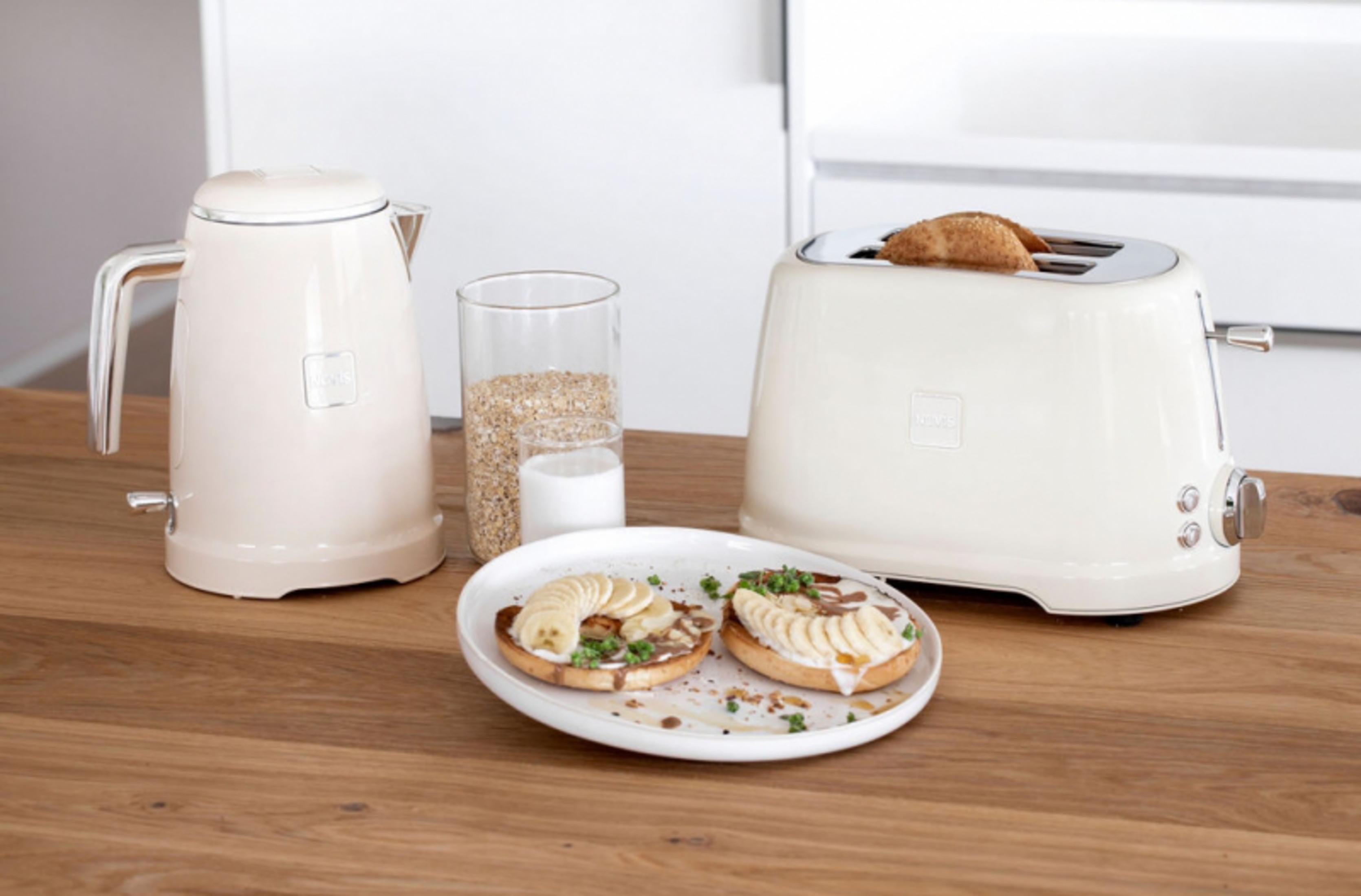 Bouilloire crème, grille-pain, flocons d'avoine et bagels banane sur table en bois.