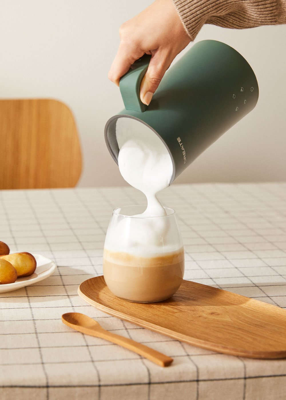 La espuma se vierte de una jarra verde a un vaso de café.