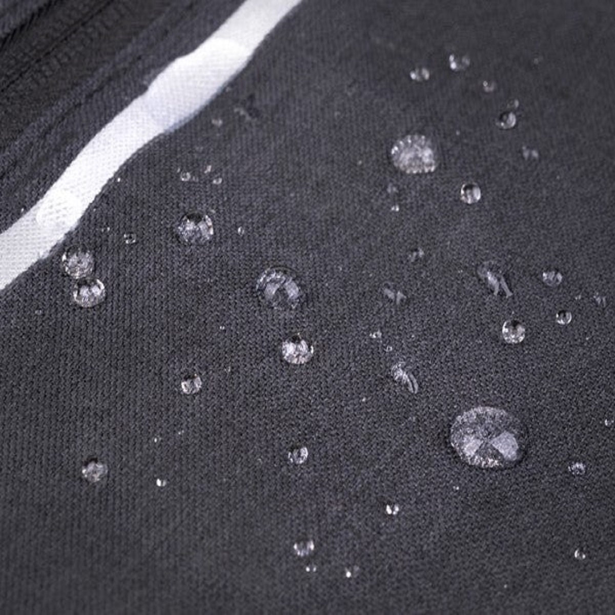 Gotas de agua sobre tela oscura con raya blanca.