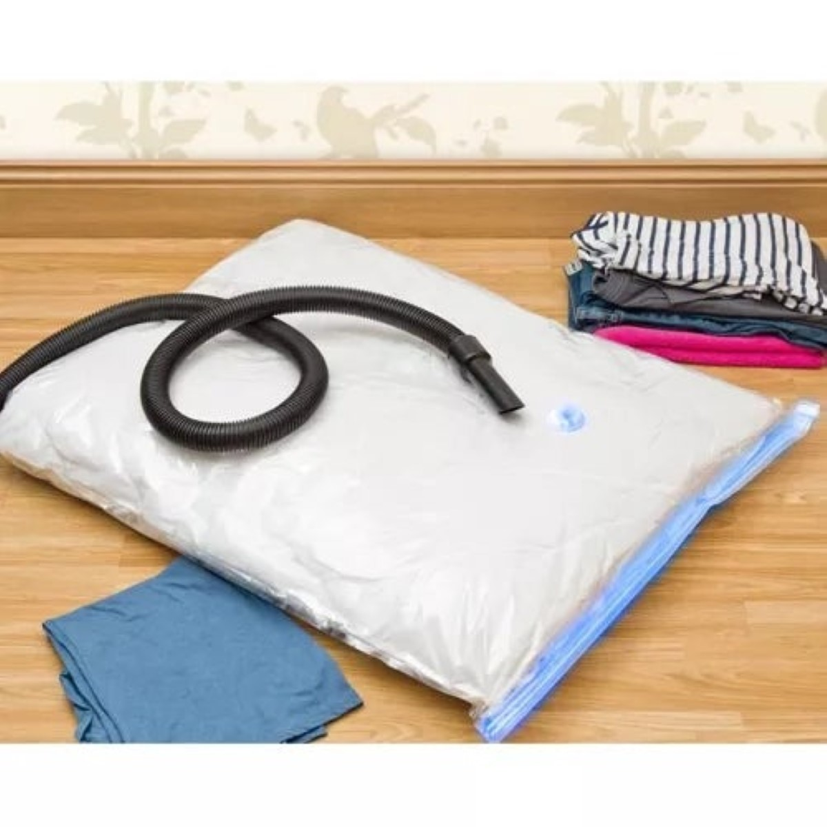 Una bolsa de vacío con manguera y ropa en suelo de madera.