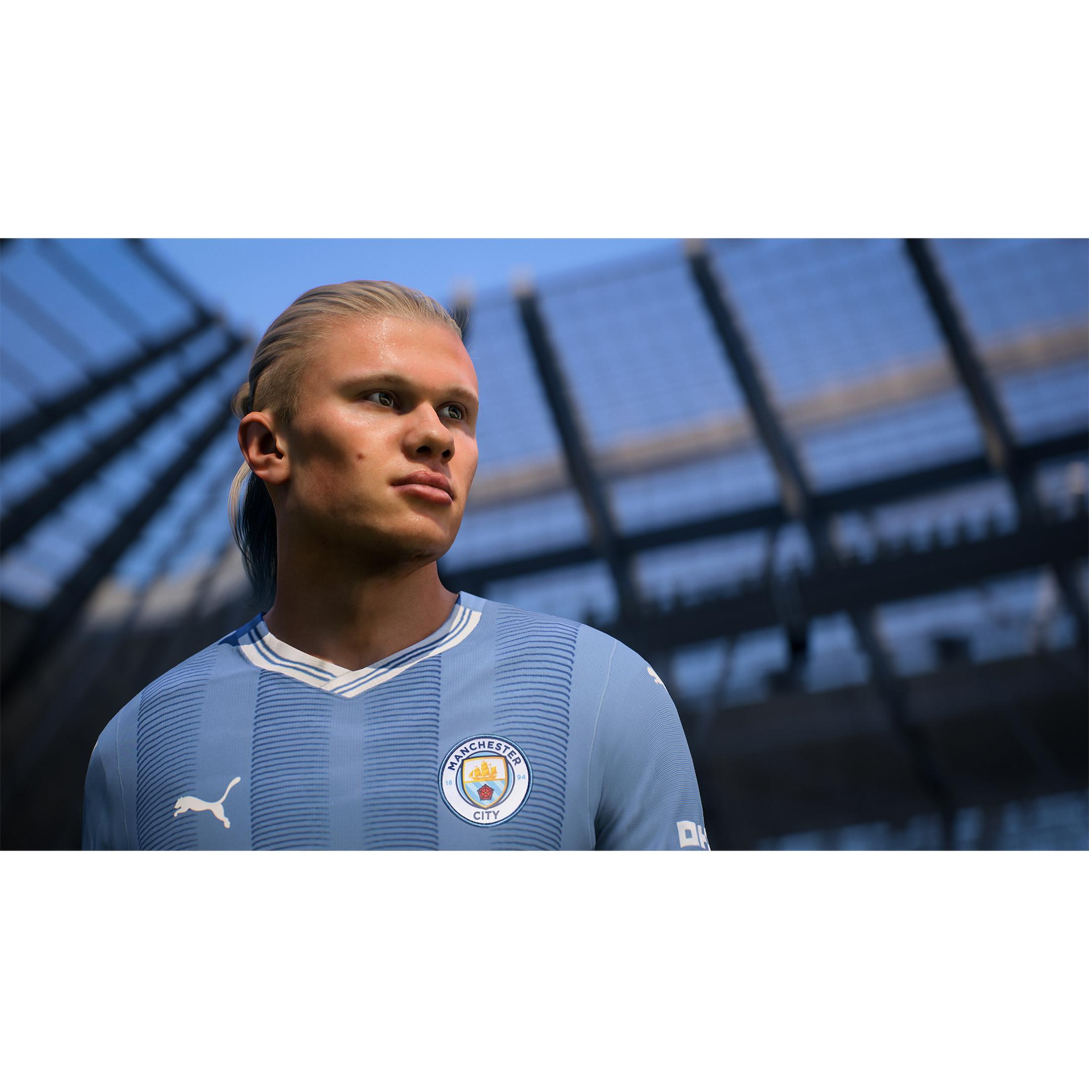Un uomo biondo in maglia da calcio azzurra, con uno stadio sullo sfondo.