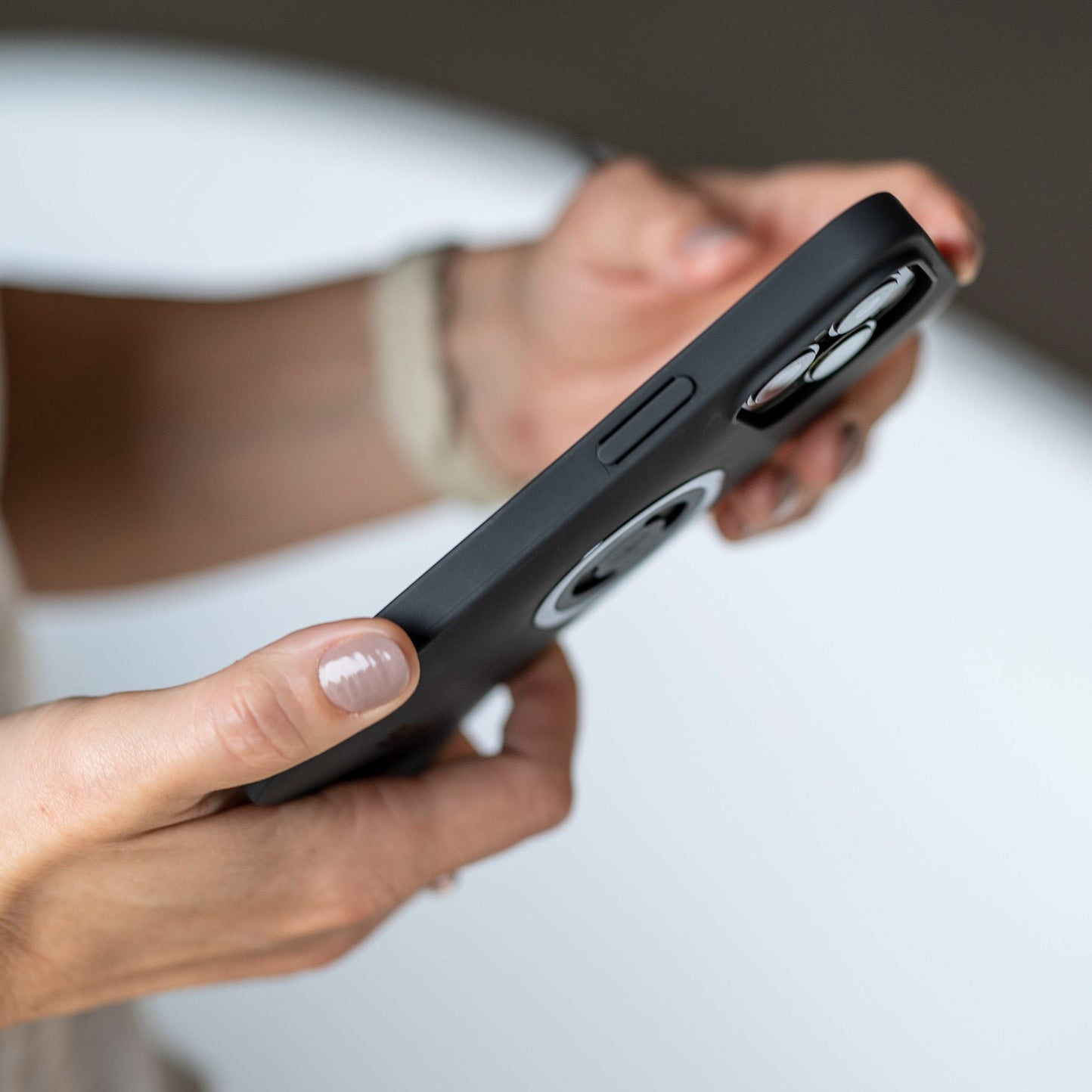 Eine Person hält ein schwarzes Smartphone mit einer Kamera mit drei Linsen.