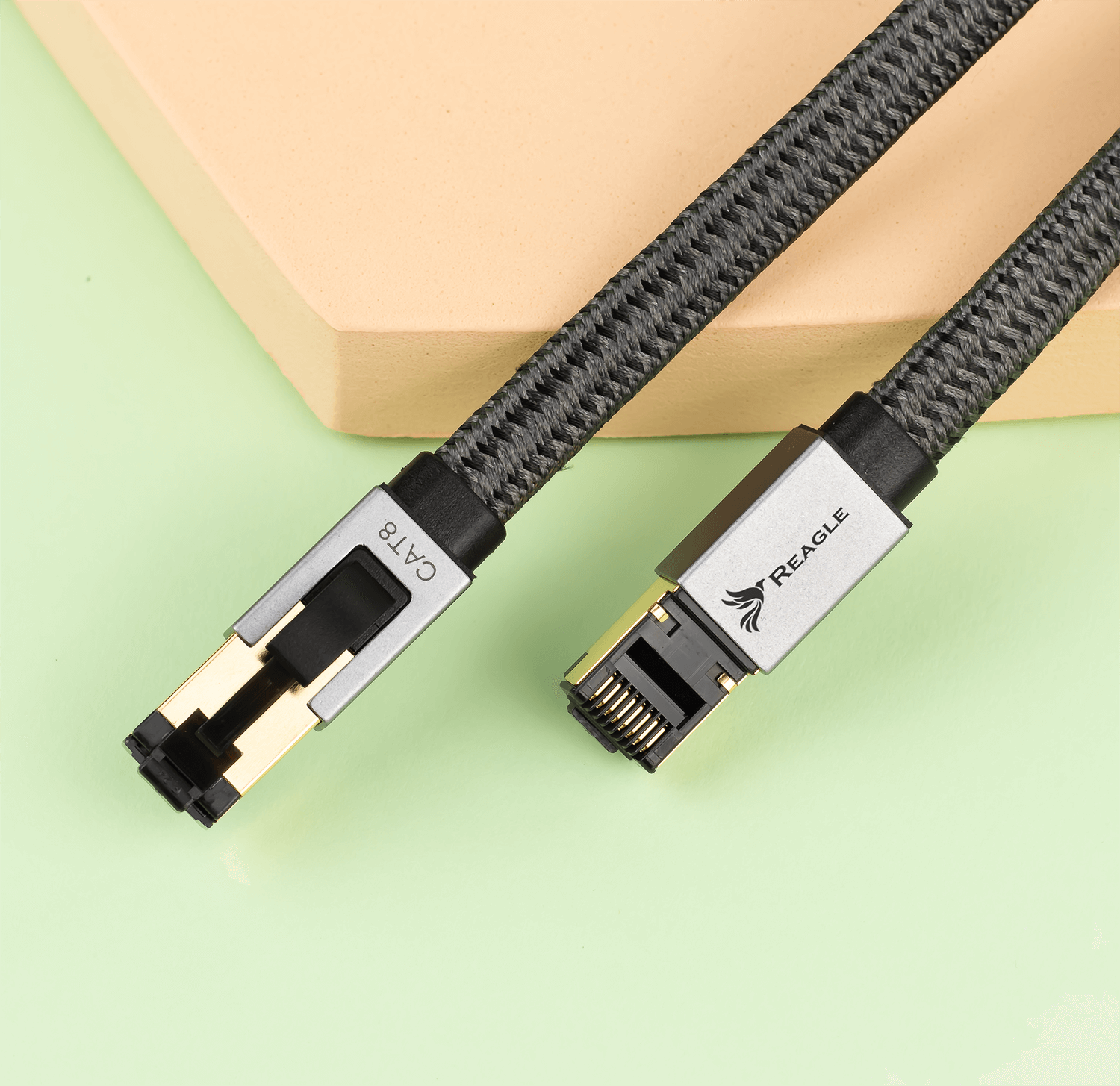Szary kabel Ethernet CAT8 ze srebrnymi złączami, jeden z napisem 'REAGLE'.