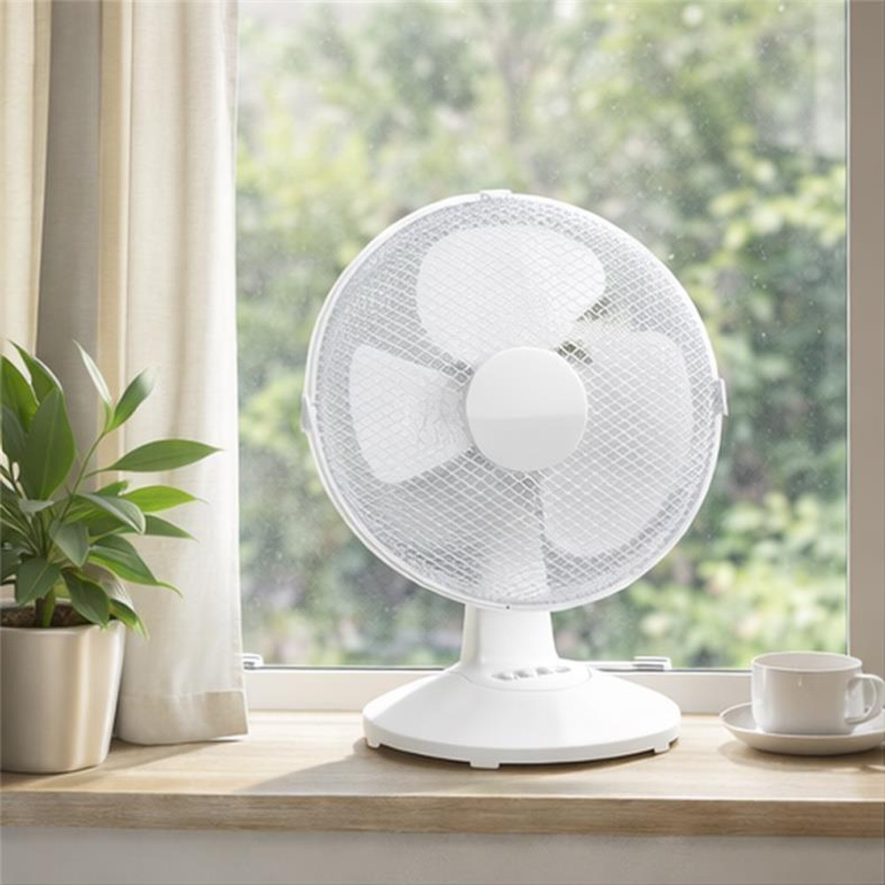 Un ventilador blanco sobre una repisa de madera junto a una ventana. Una planta y una taza cerca.