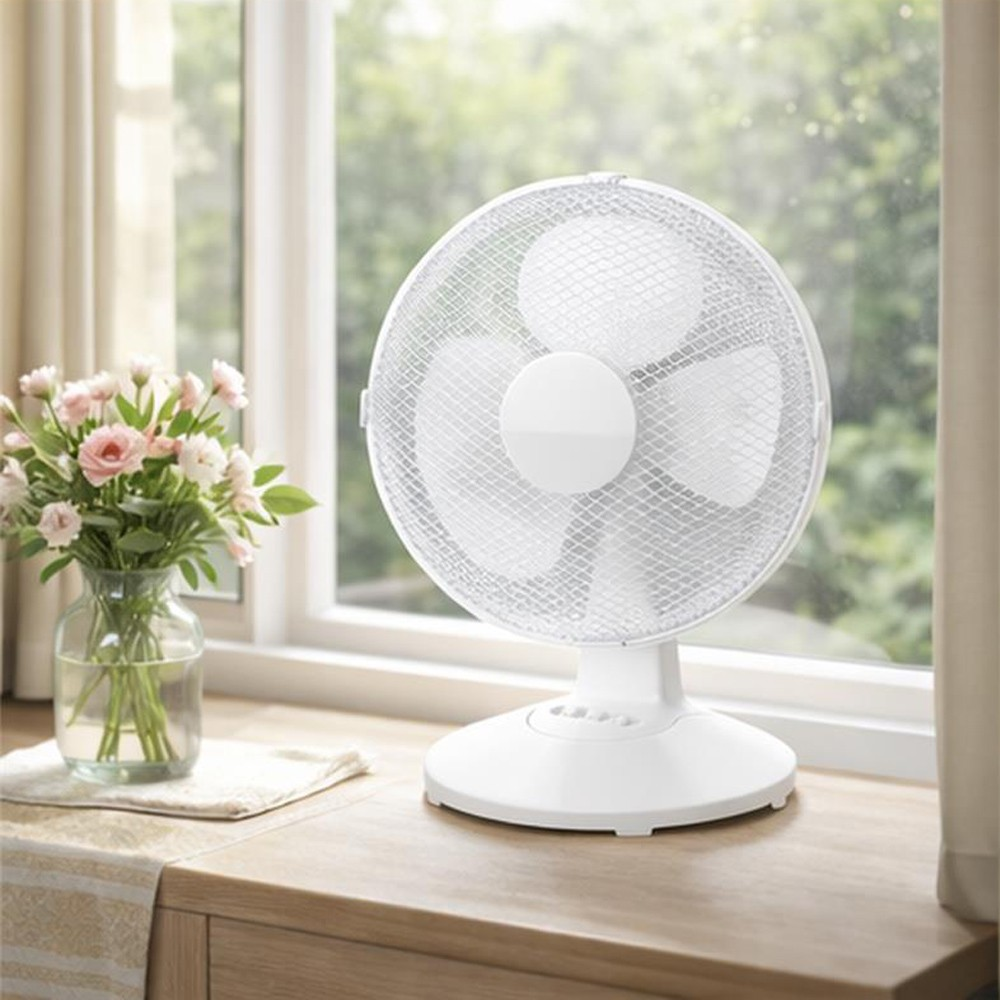 Un ventilador de escritorio blanco se asienta en un alféizar de ventana de madera junto a un jarrón de flores rosas.
