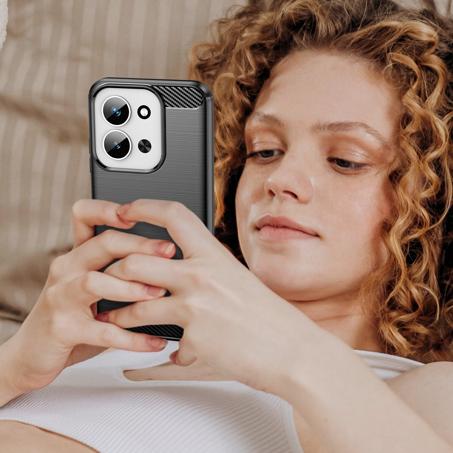 Una mujer con cabello rizado sostiene un smartphone en funda negra.