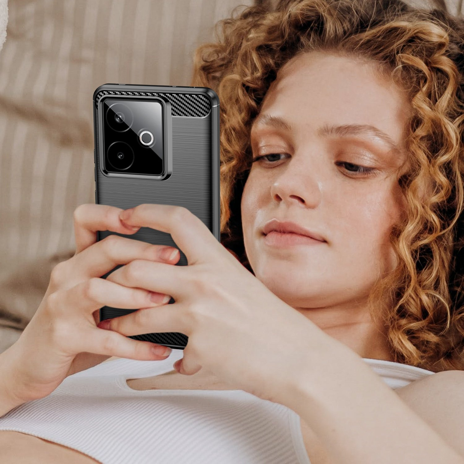 Una mujer con cabello rizado sostiene un smartphone negro con módulo de cámara.