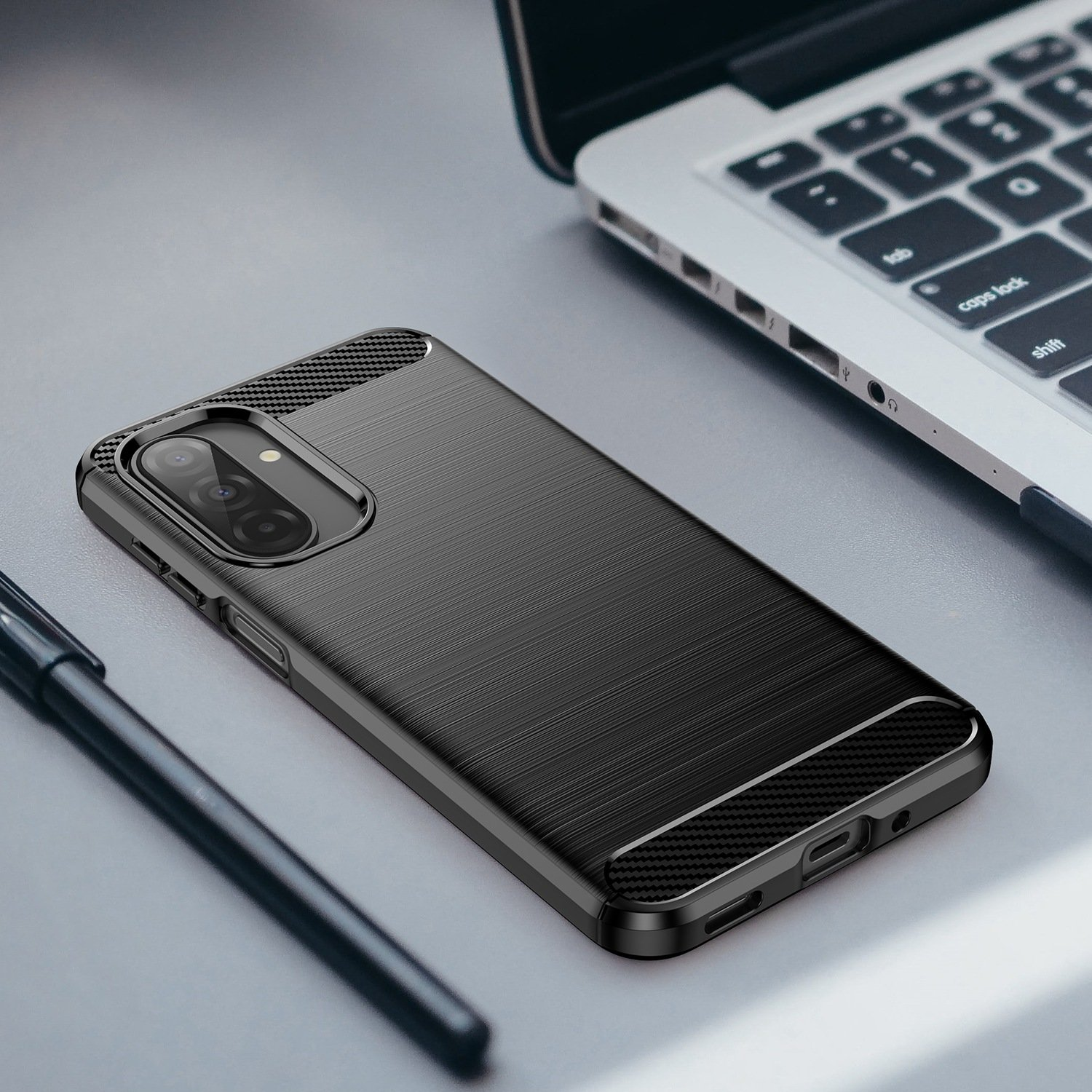 Funda negra para teléfono con textura cepillada junto a un portátil y un bolígrafo.