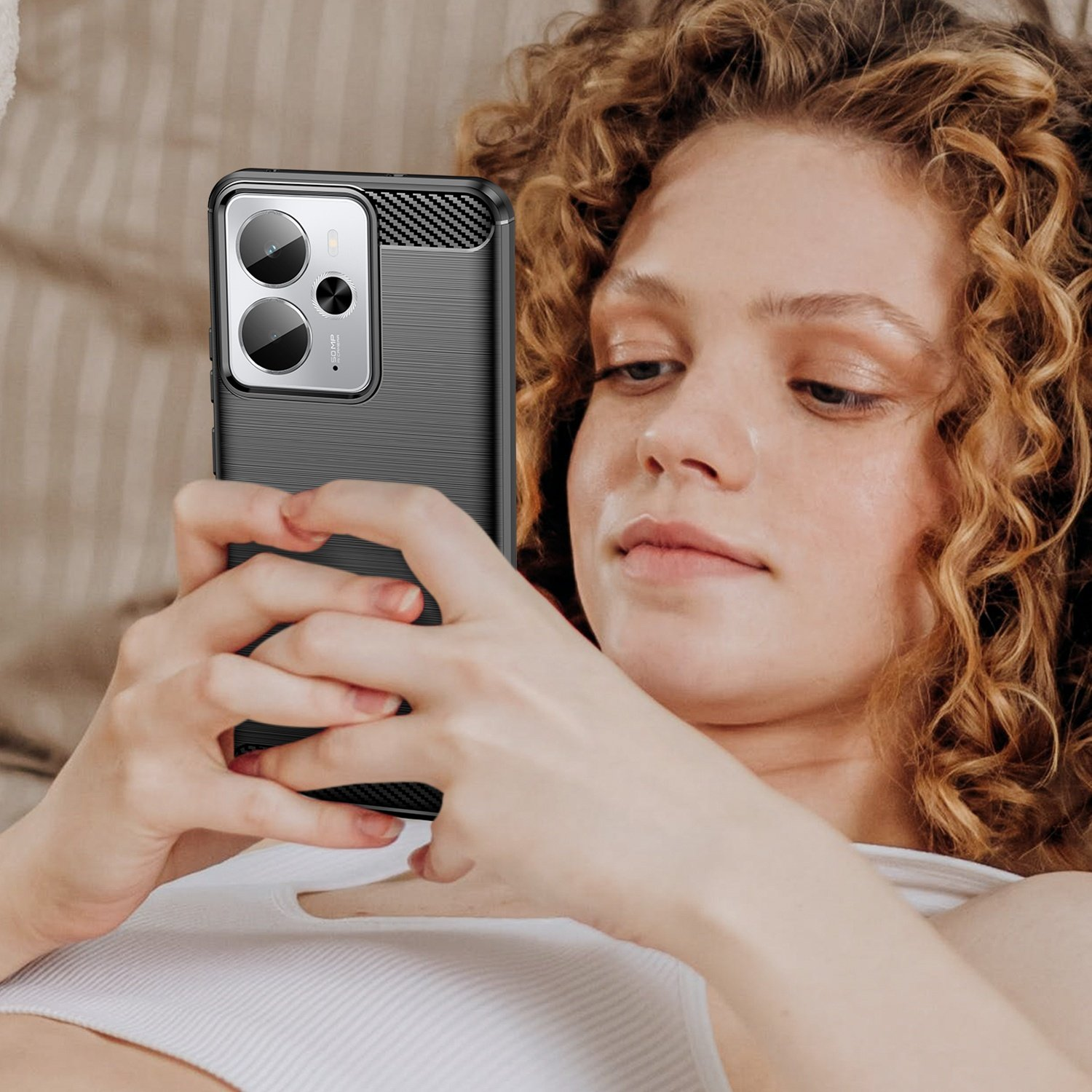 Una mujer con cabello rizado sostiene un smartphone con funda negra.