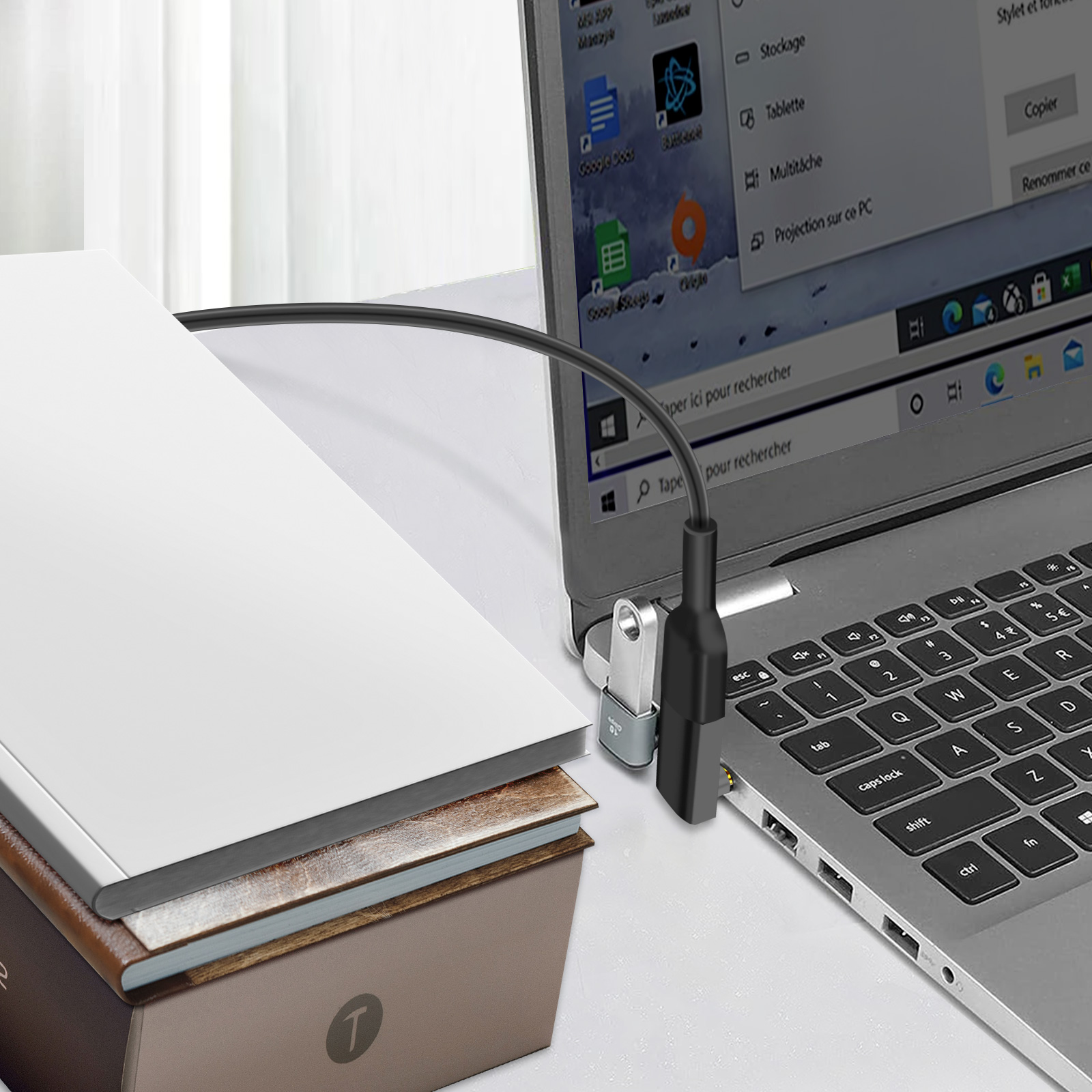 Un'unità USB è collegata a un laptop; ci sono libri accanto.