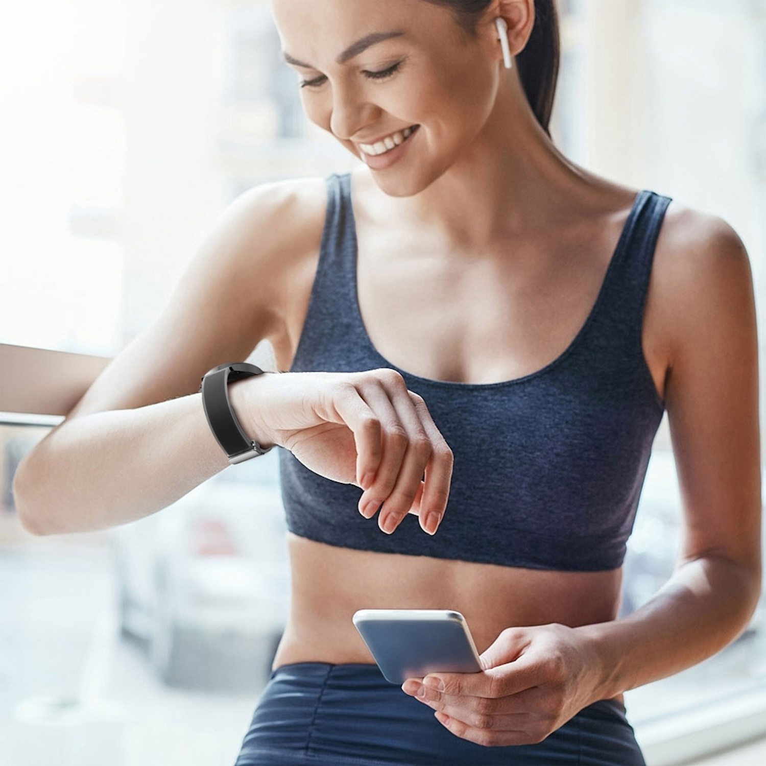 Frau mit Kopfhörern und Smartwatch hält Handy.