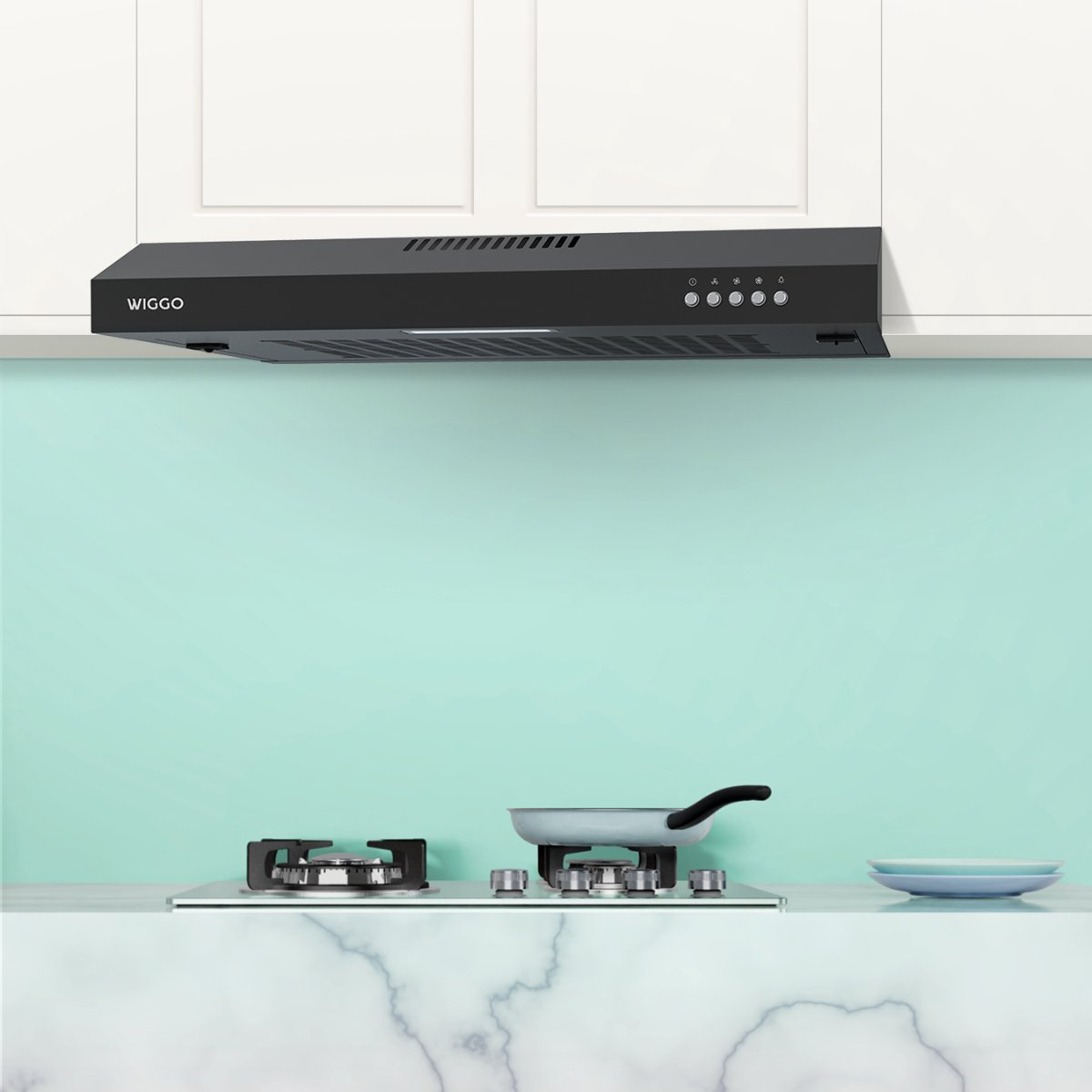 A black WIGGO range hood above a gas stove with a frying pan. Light blue plates are nearby.