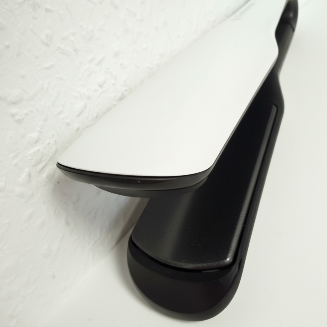 Ein weißer und schwarzer Haarglätter mit flachen Platten liegt auf einer weißen Oberfläche.