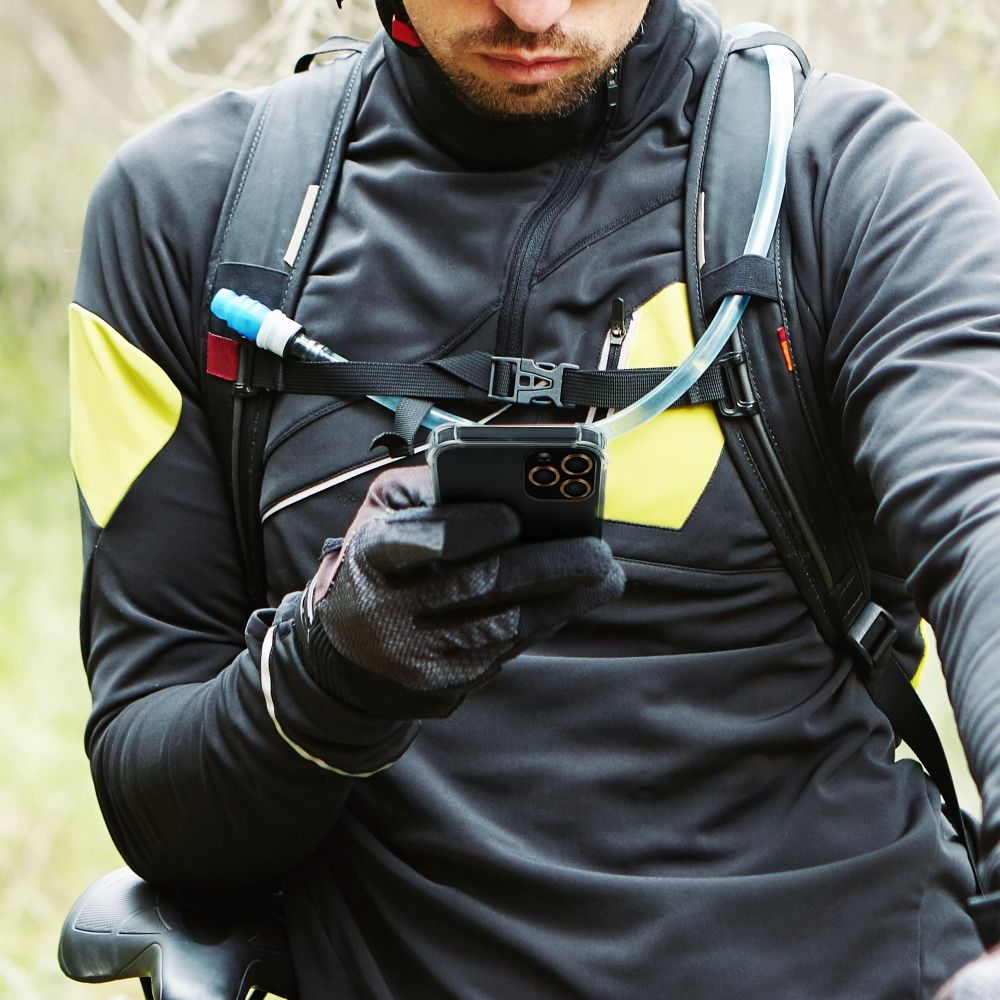 Ein Mann mit Rucksack und Handy in der Hand, beim Mountainbiken.
