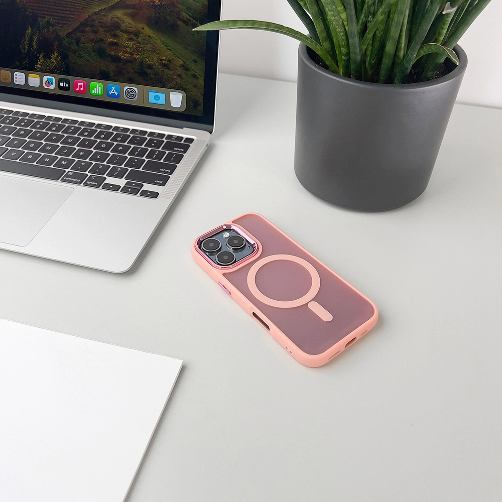 Ein rosafarbener iPhone-Kasten liegt neben einem Laptop und einer Topfpflanze.
